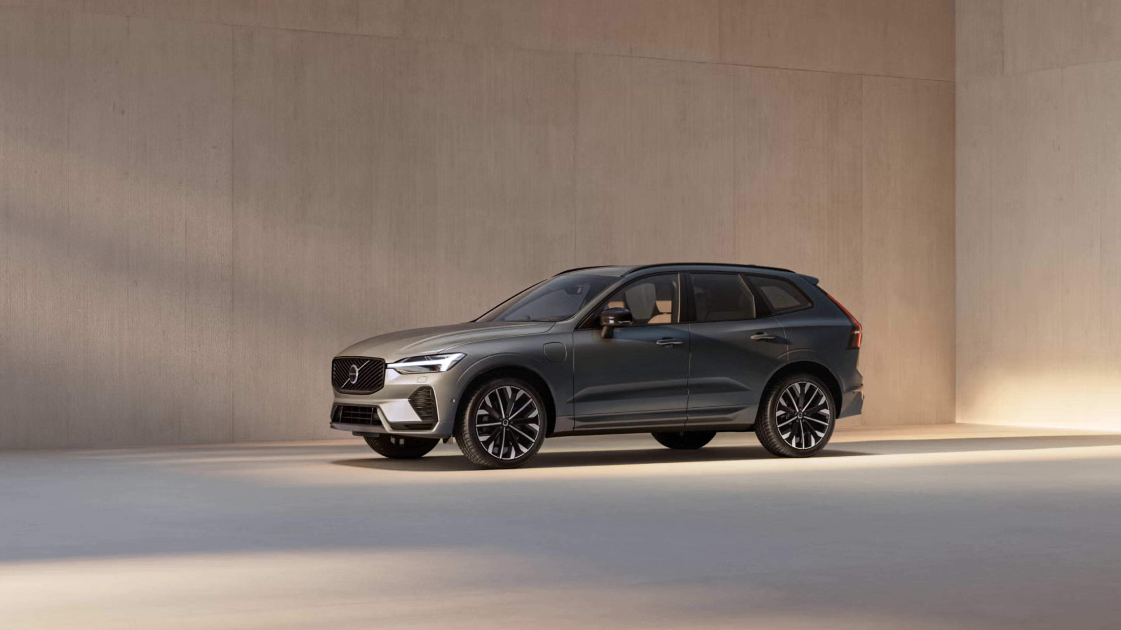 XC60 plug-in hybrid at three quarter angle in front of pastel concrete wall bathed in soft daylight
