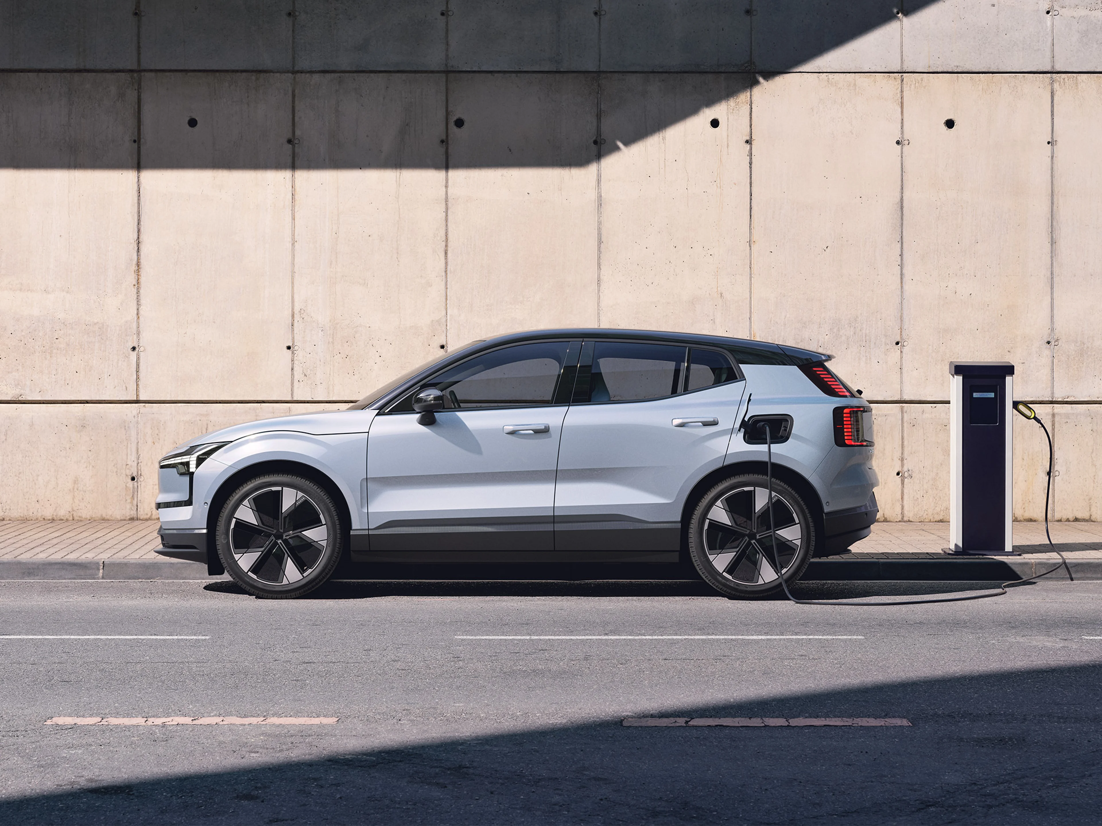 Cloud Blue -värinen Volvo EX30 täyssähköauto kytkettynä lataukseen.