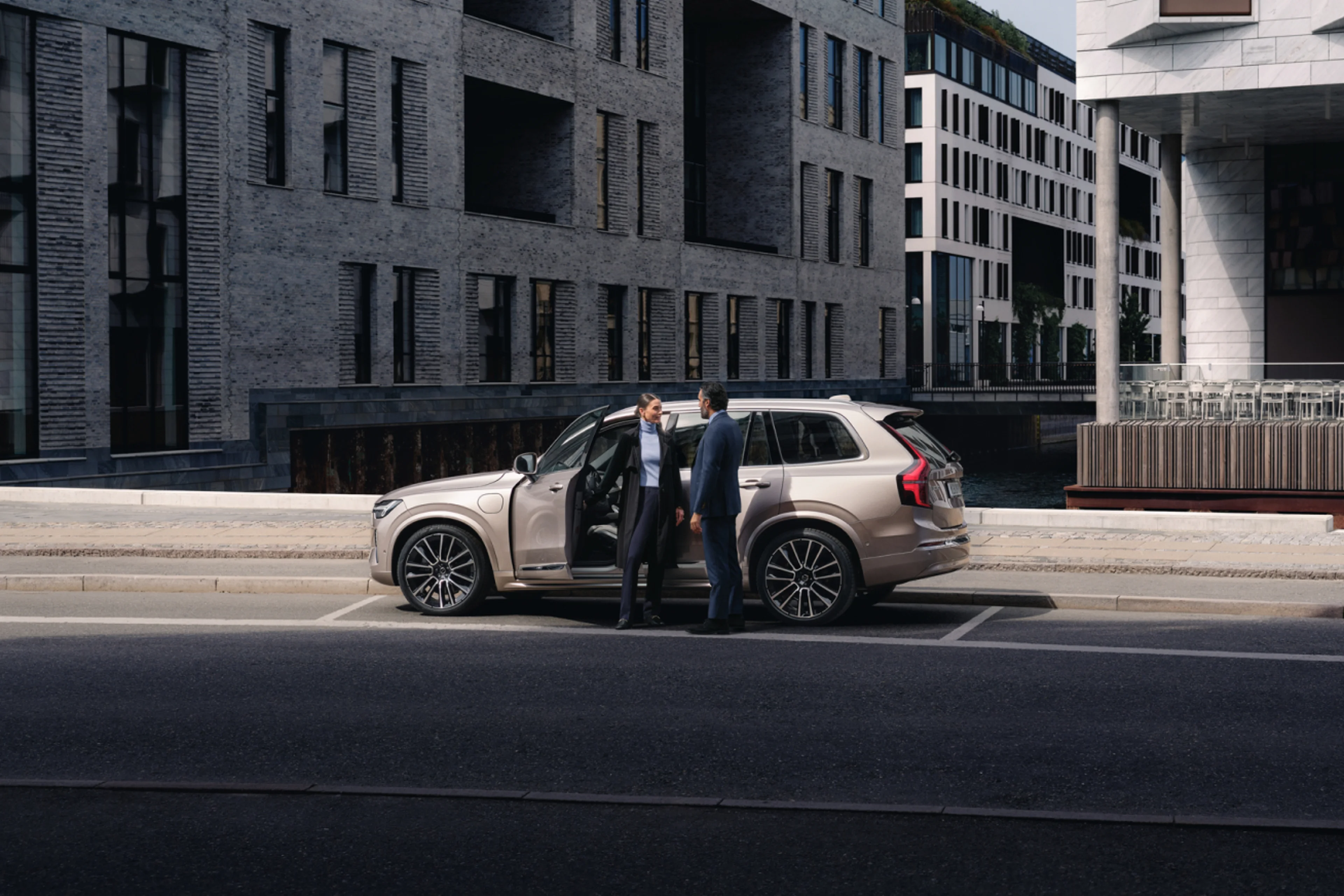 Two people standing on the side of the opened door of a car