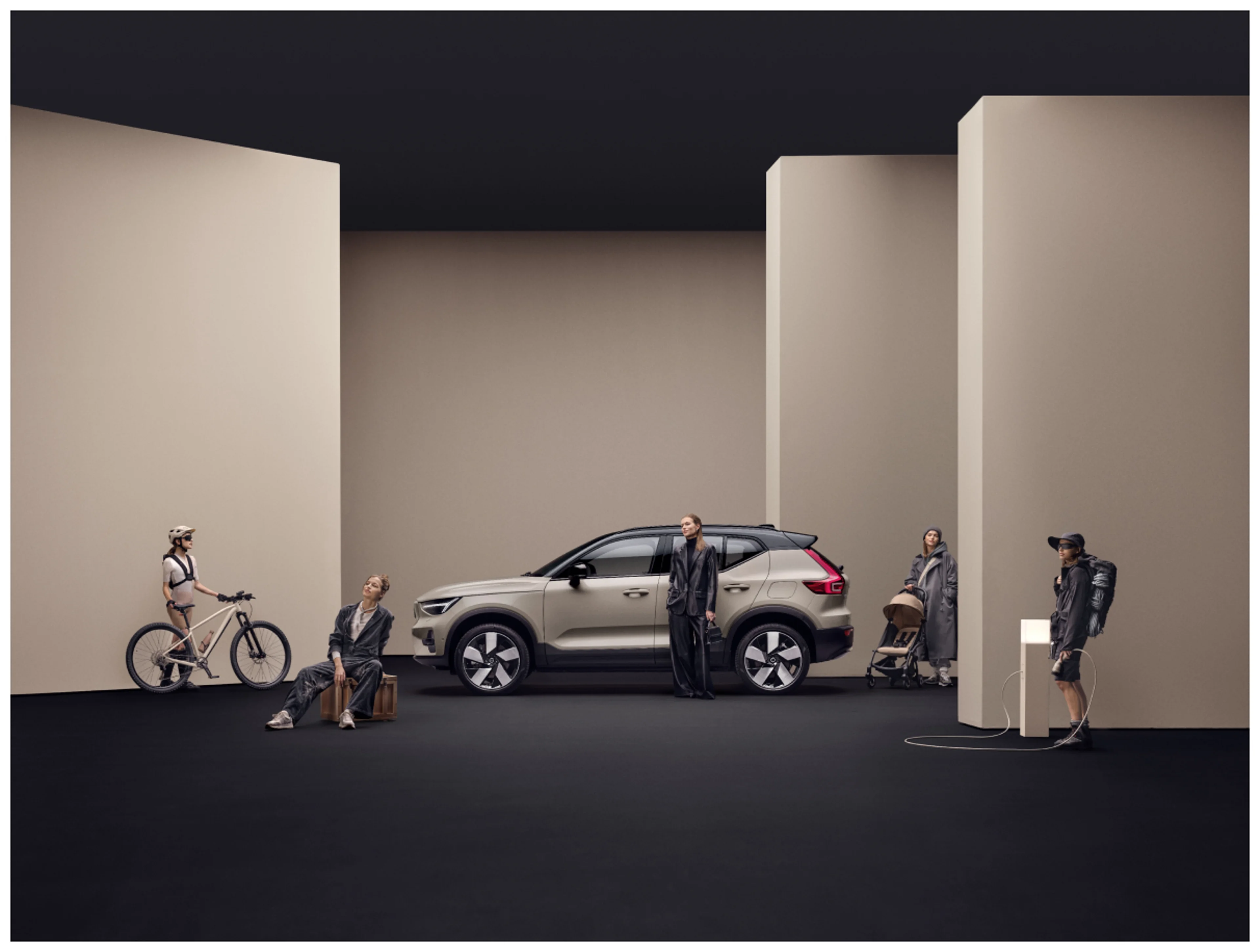 A beige Volvo SUV in a minimalist interior setting, surrounded by various people representing different lifestyles.