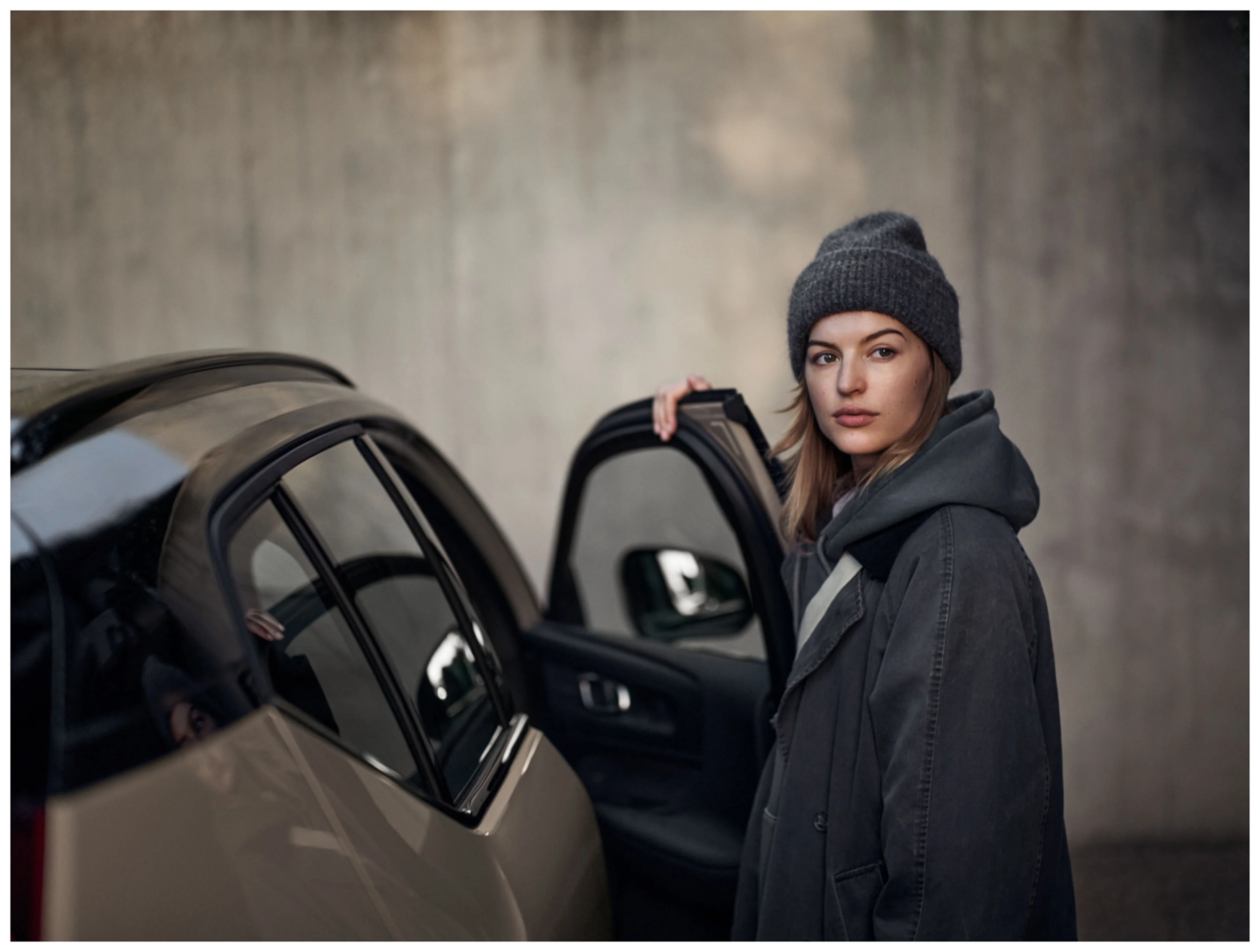 A woman standing on the opening front door of a car.
