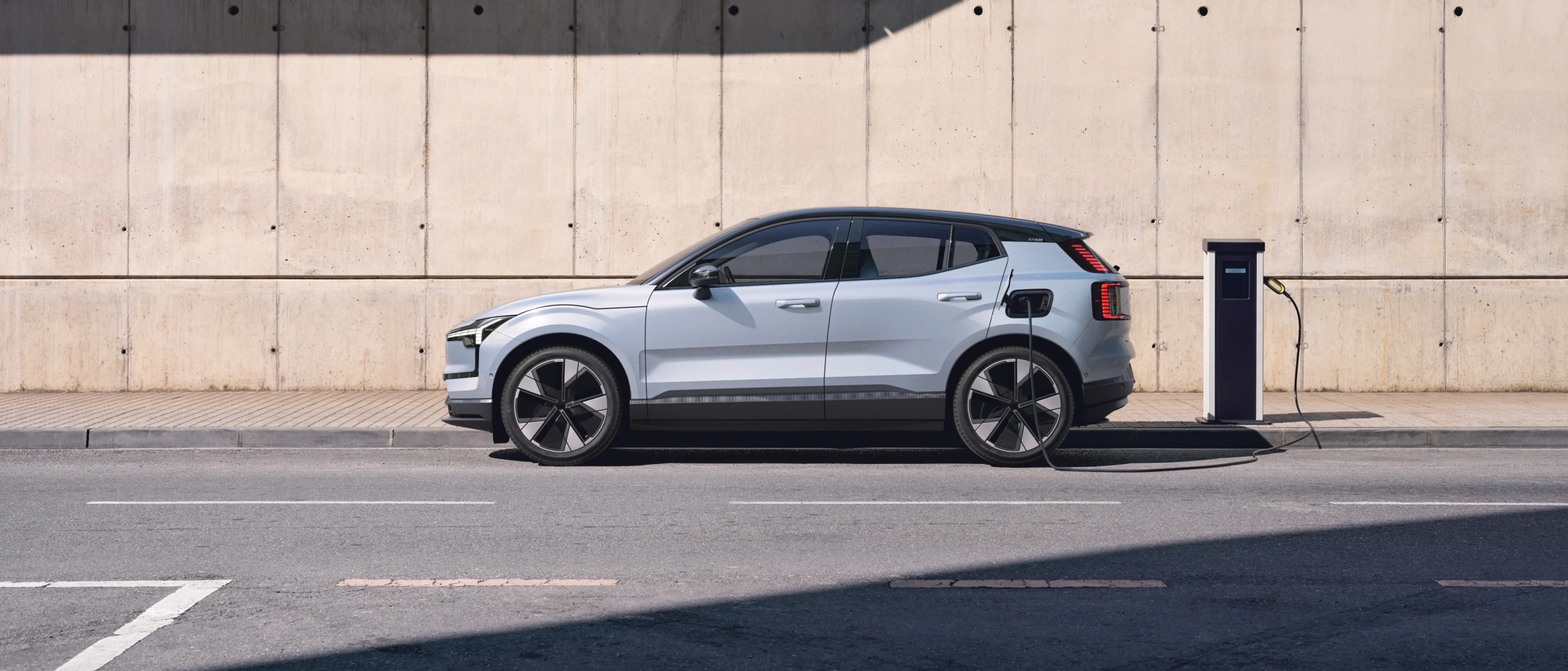 Το προφίλ ενός Volvo EX30 που φορτίζεται σε αστικό περιβάλλον.