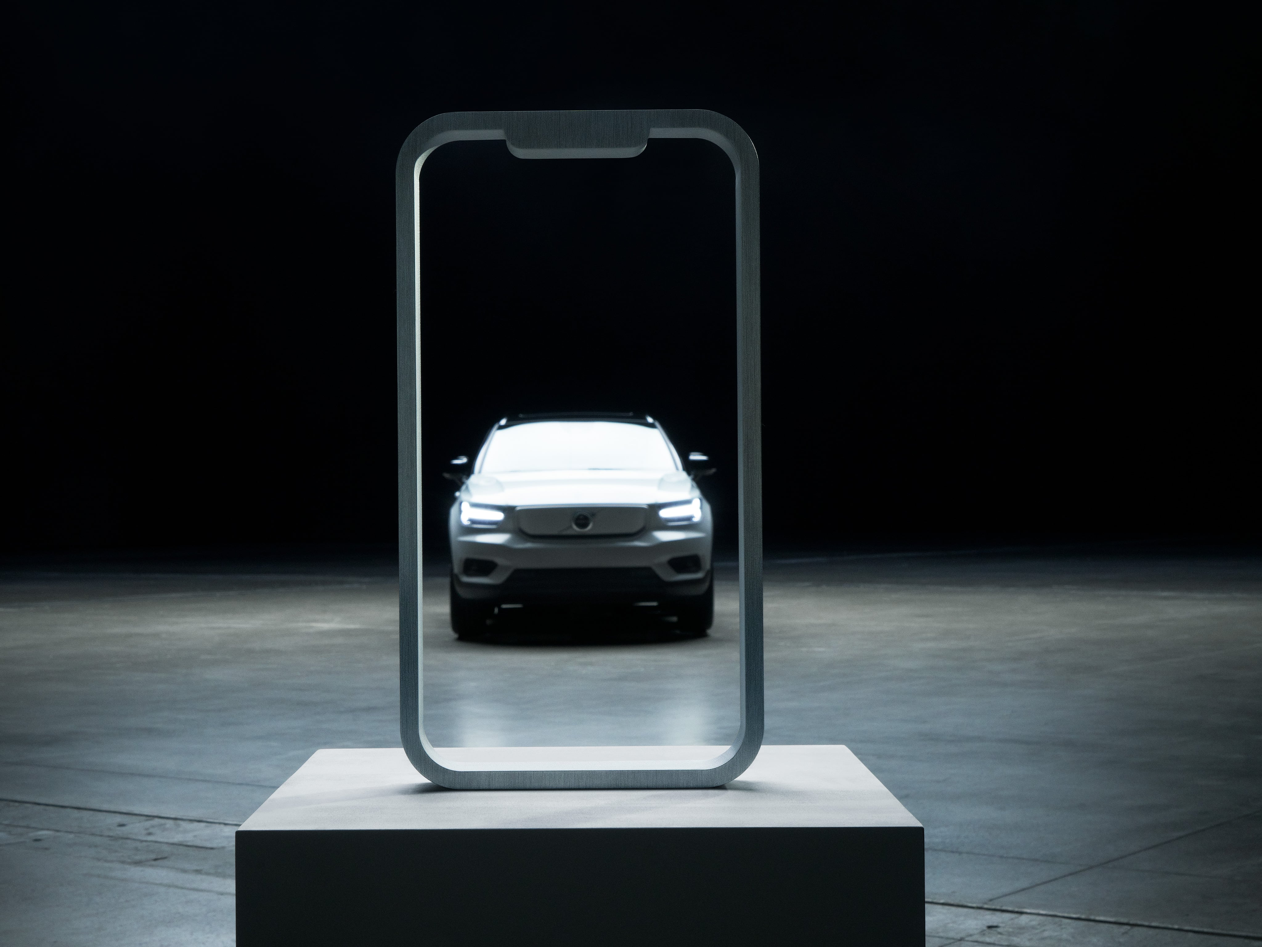 Une Volvo XC40 Recharge entourée par le cadre d’un écran mobile posé sur un podium.