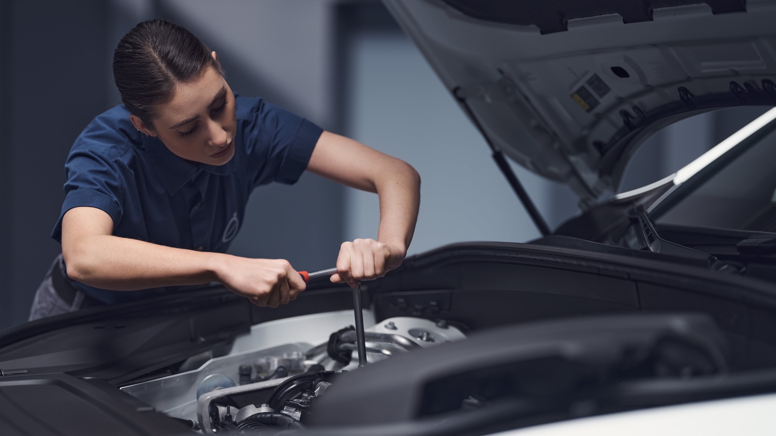Close up of female Volvo technician working on an engine.