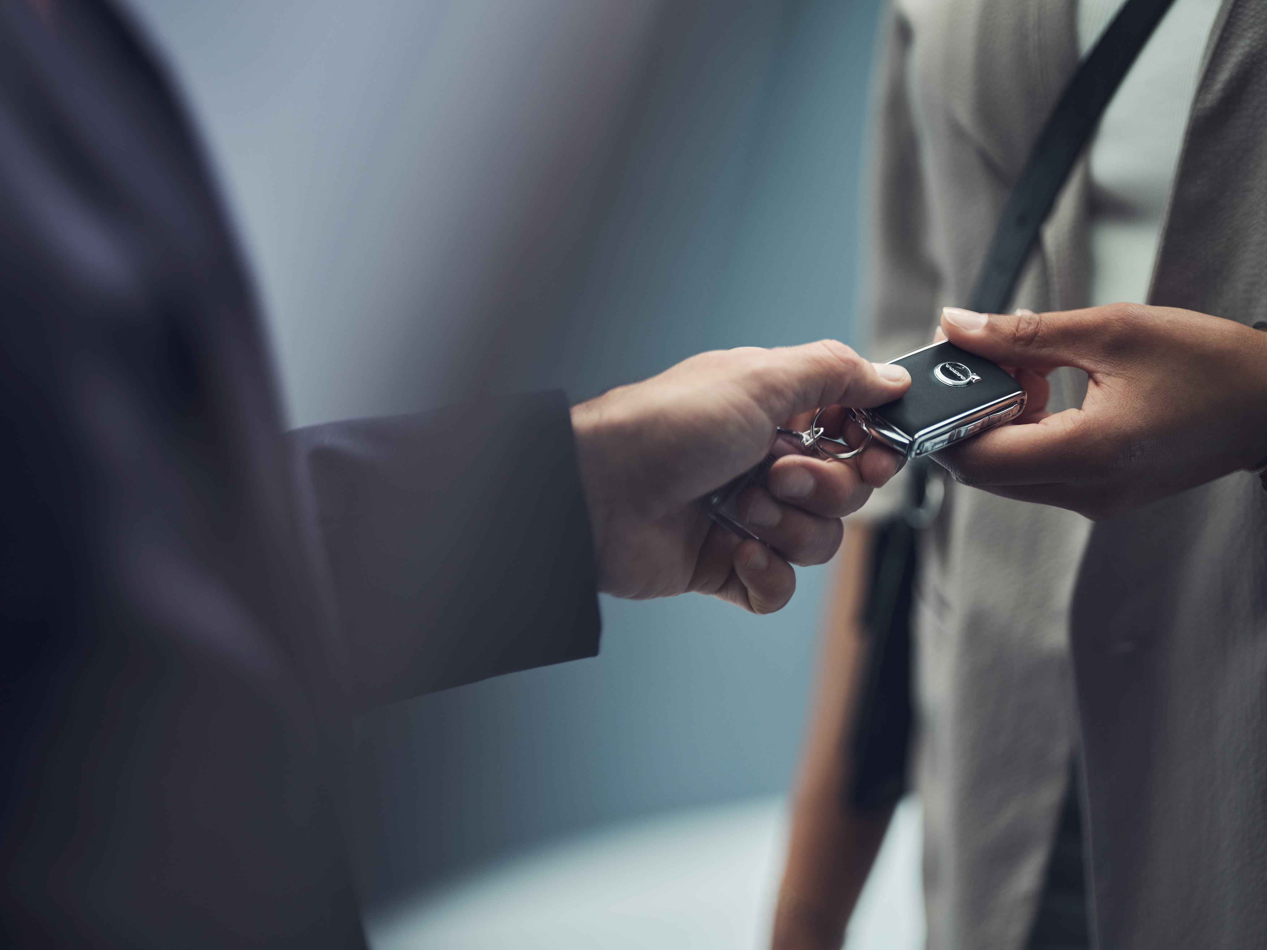 Een persoon overhandigt een Volvo-sleutel aan een andere persoon.