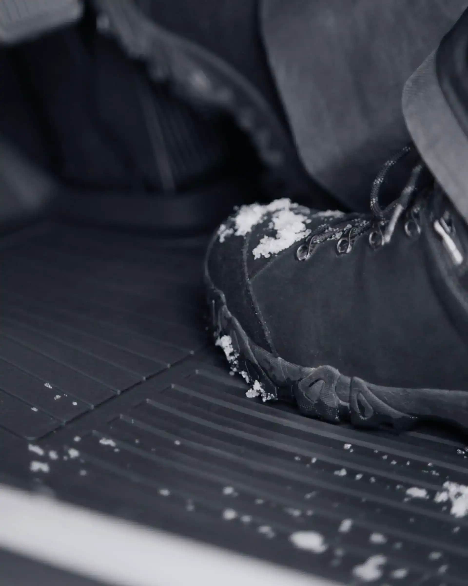 Pohled zblízka na sněhem pokrytou nohu na koberečku vhodném do každého počasí ve voze Volvo.