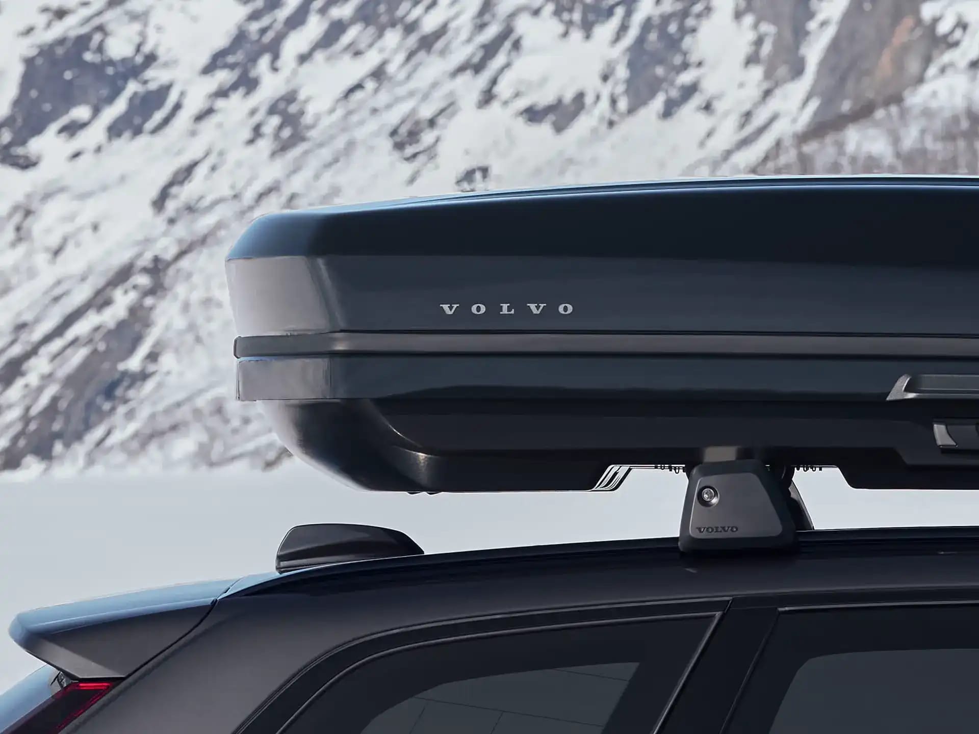 Značkový střešní box Volvo na střeše vozu Volvo zaparkovaného v zimní krajině.