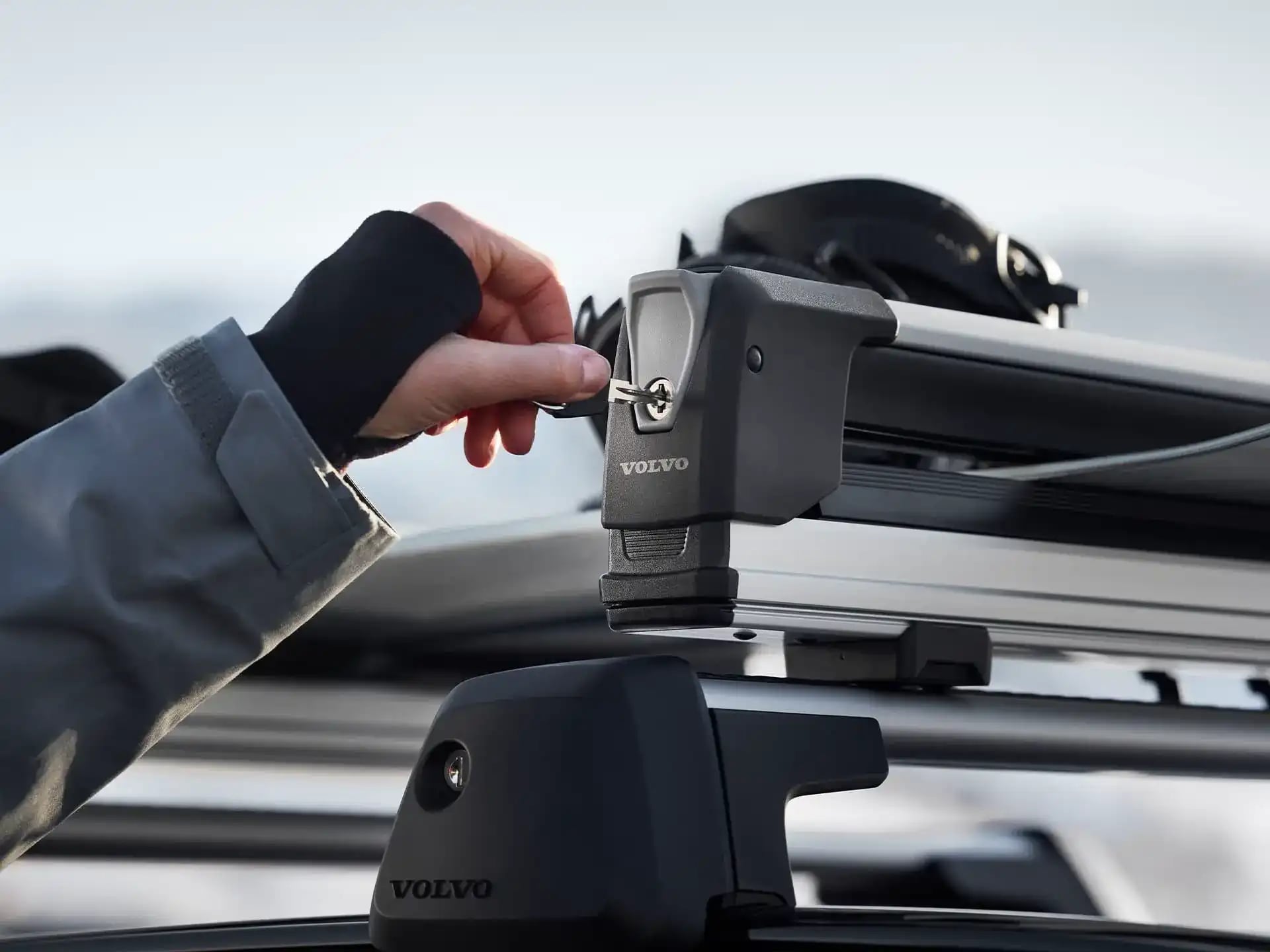 Ruka otáčející klíčem při zamykání nosiče lyží Volvo v zimním prostředí.