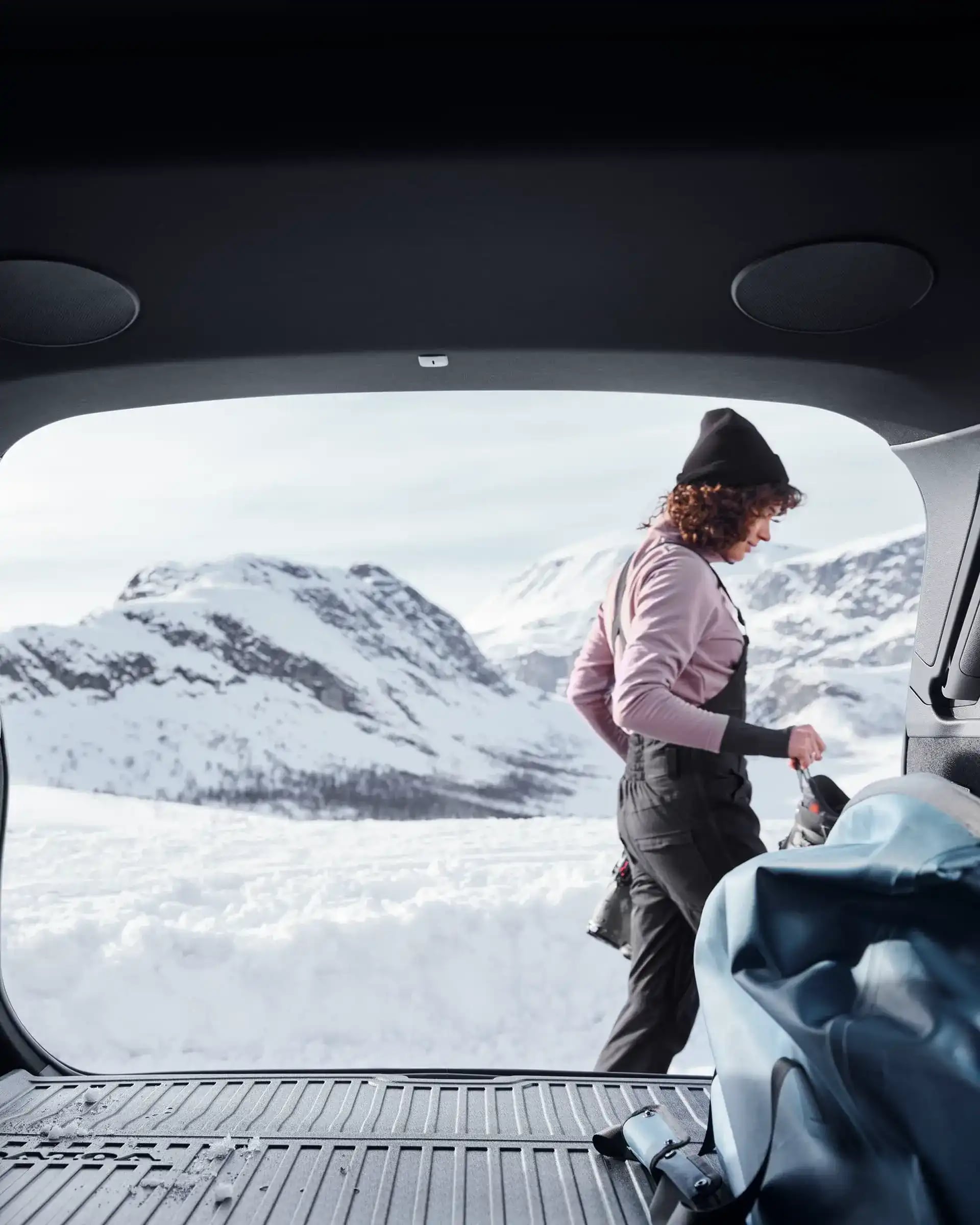 Cestovatel ukládající vybavení do zadního zavazadlového prostoru vozu Volvo XC60 vybaveném zimním příslušenstvím.