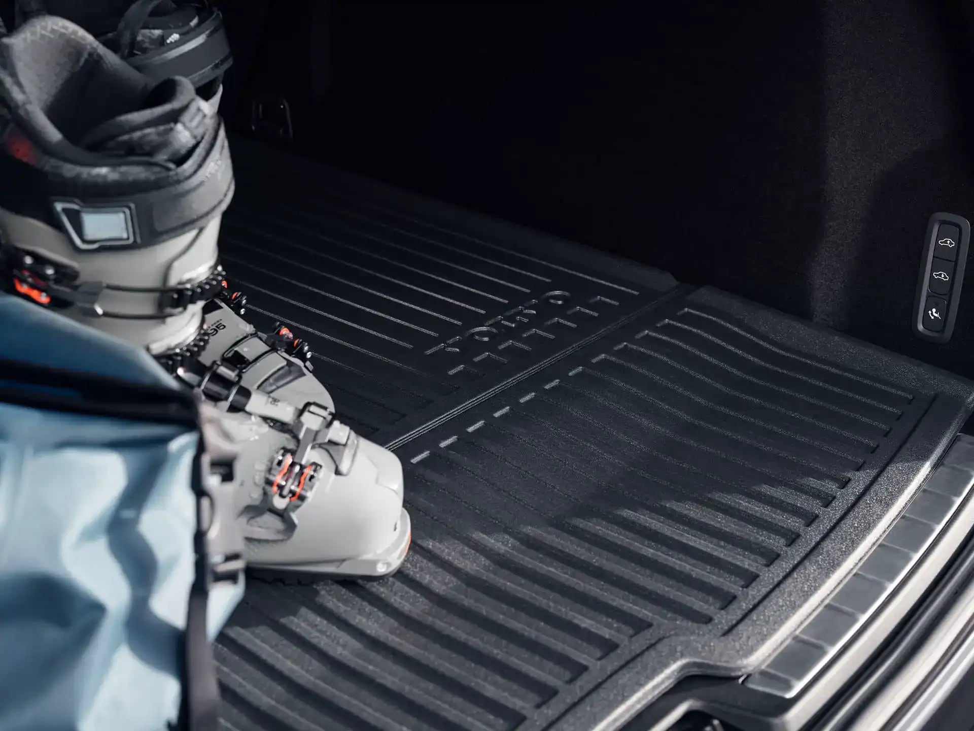Zimní obuv a taška na podložce v zavazadlovém prostoru vozu Volvo.