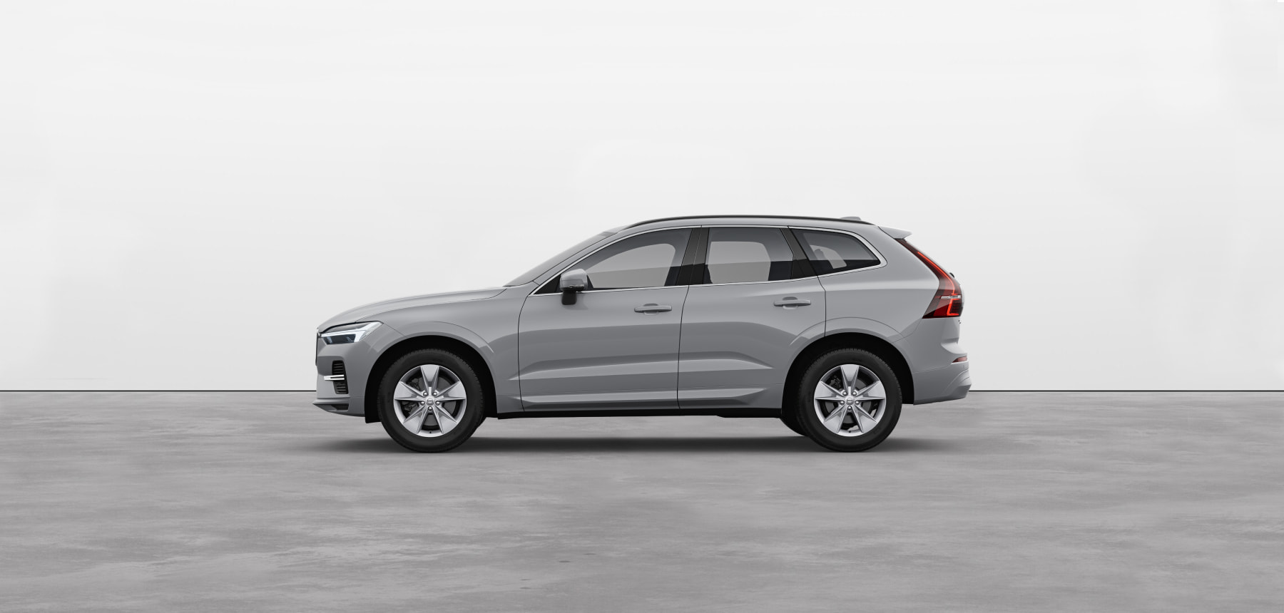 A vapour grey Volvo XC60 SUV standing still on grey floor in a studio.