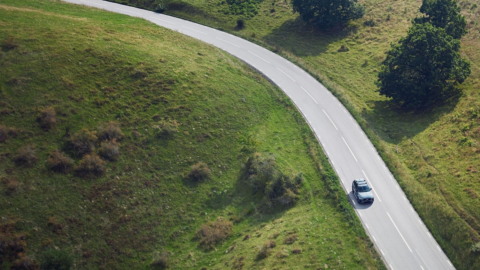 A Volvo is seen moving along a path of beautiful greenery from above.