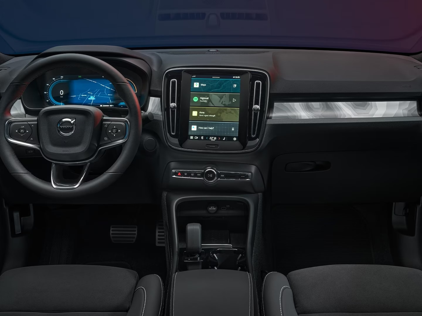 Vista interior de los asientos delanteros del Volvo C40 Recharge con volante, pantalla del conductor y pantalla central.