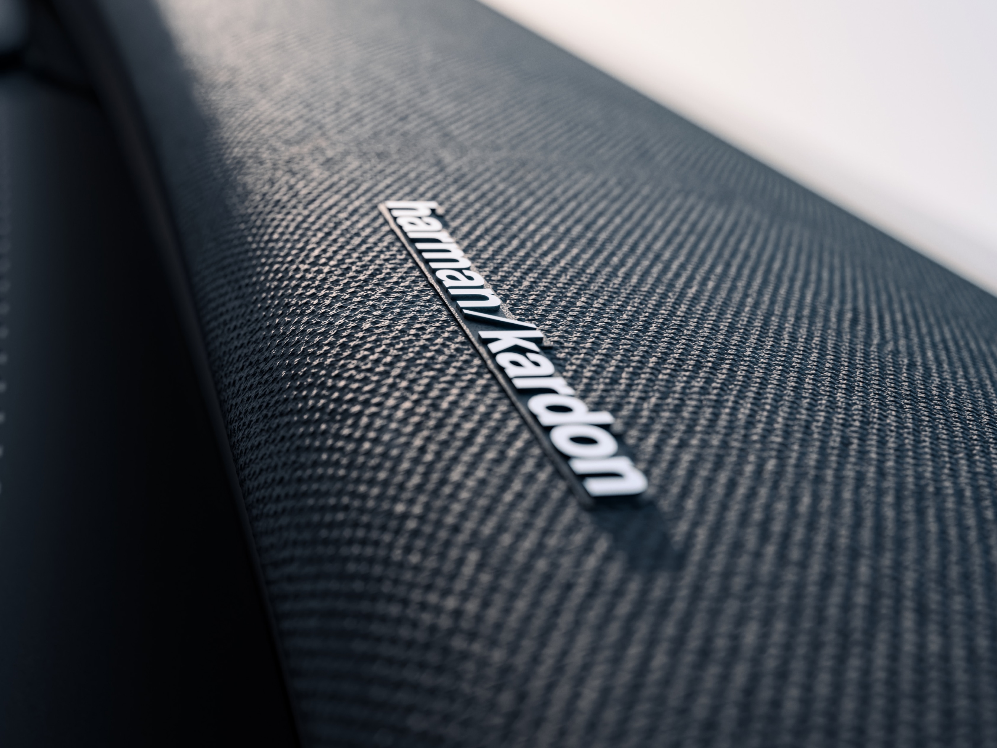 Närbild av logotypen på en högtalare från Harmon Kardon i en Volvo EX30
