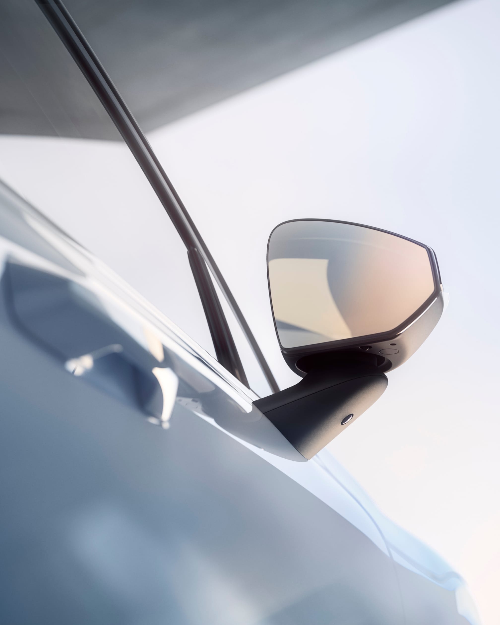 Bezrámové vnější zpětné zrcátko vozu Volvo EX30 na straně spolujezdce lesknoucí se v jasném slunečním světle.