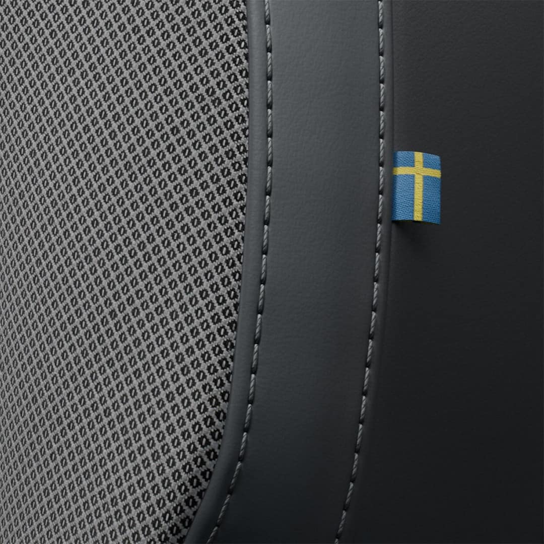 Pohled zblízka na prošití sedadla předního spolujezdce v mild hybridním voze Volvo S60. V bočním švu sedadla je všit decentní štítek v podobě švédské vlajky.