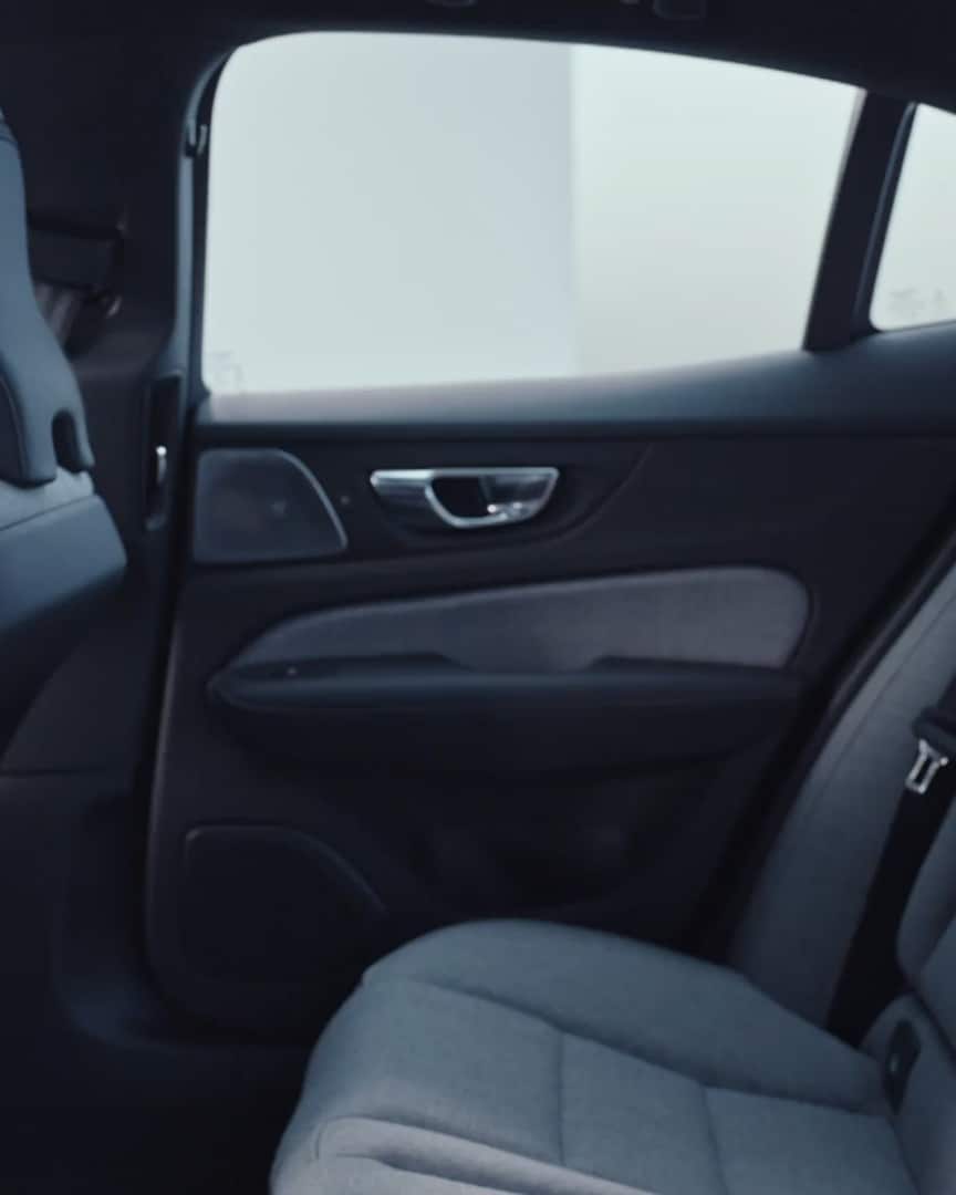 Los asientos traseros abatibles para pasajeros con tapicería textil y la consola central trasera en un Volvo S60 Recharge híbrido enchufable.