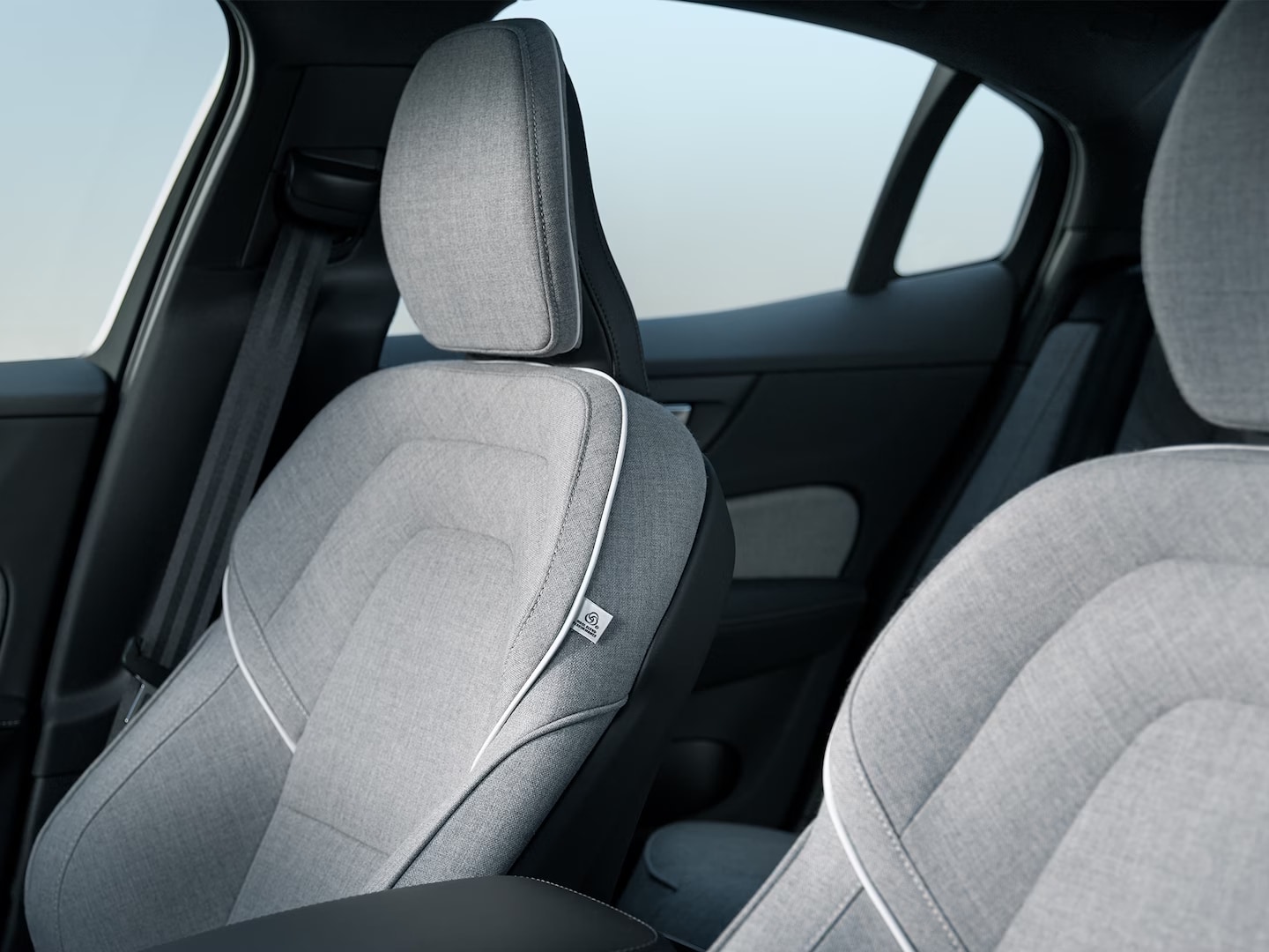 The Volvo S60 Recharge plug-in hybrid’s front passenger and driver’s seats in gray Tailored Wool Blend upholstery with white trim.