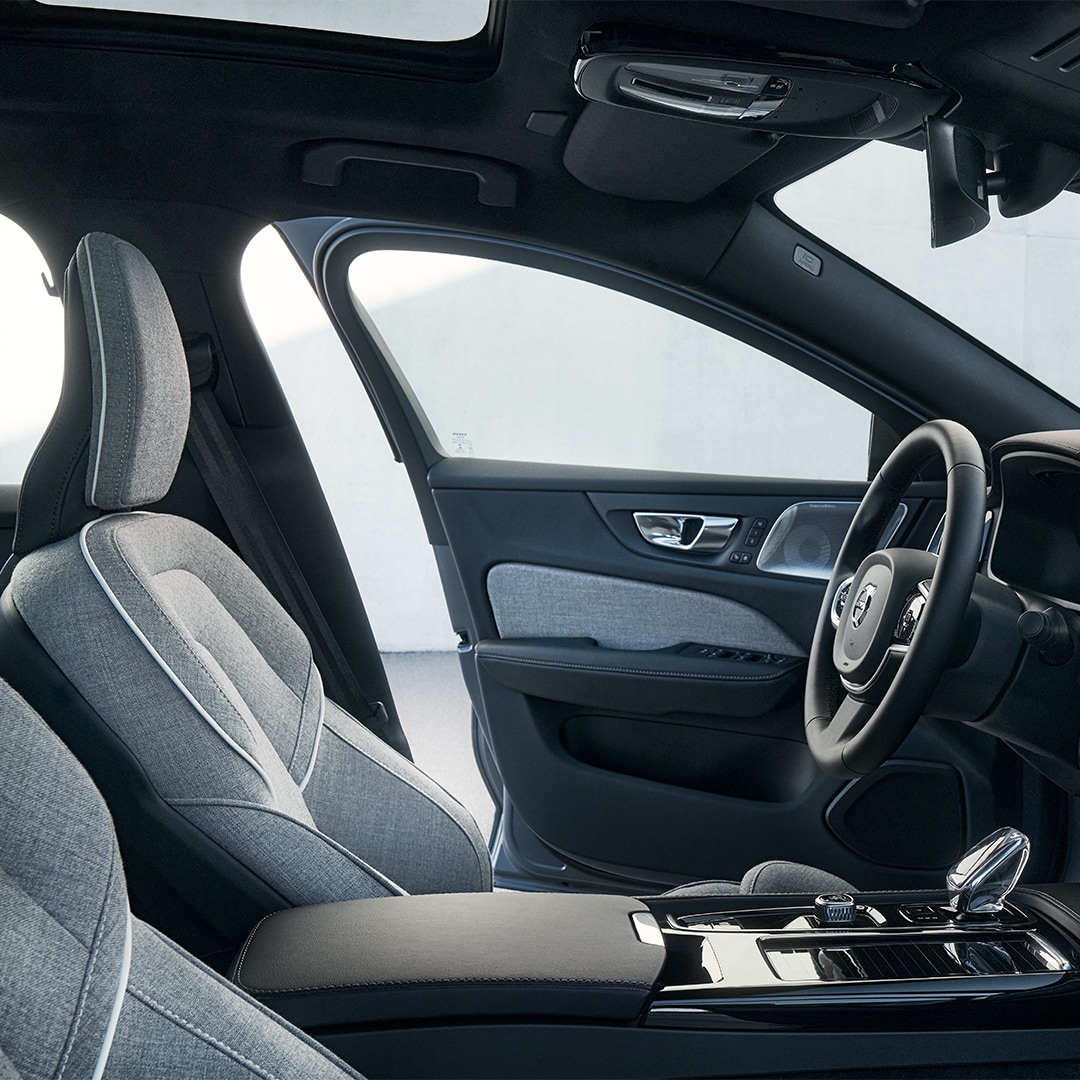 Sedadlo vodiča v interiéri plug-in hybridného vozidla Volvo S60 Recharge spolu s volantom, displejom systému infotainment, krištáľovou hlavicou voliča radenia a dverami vodiča.