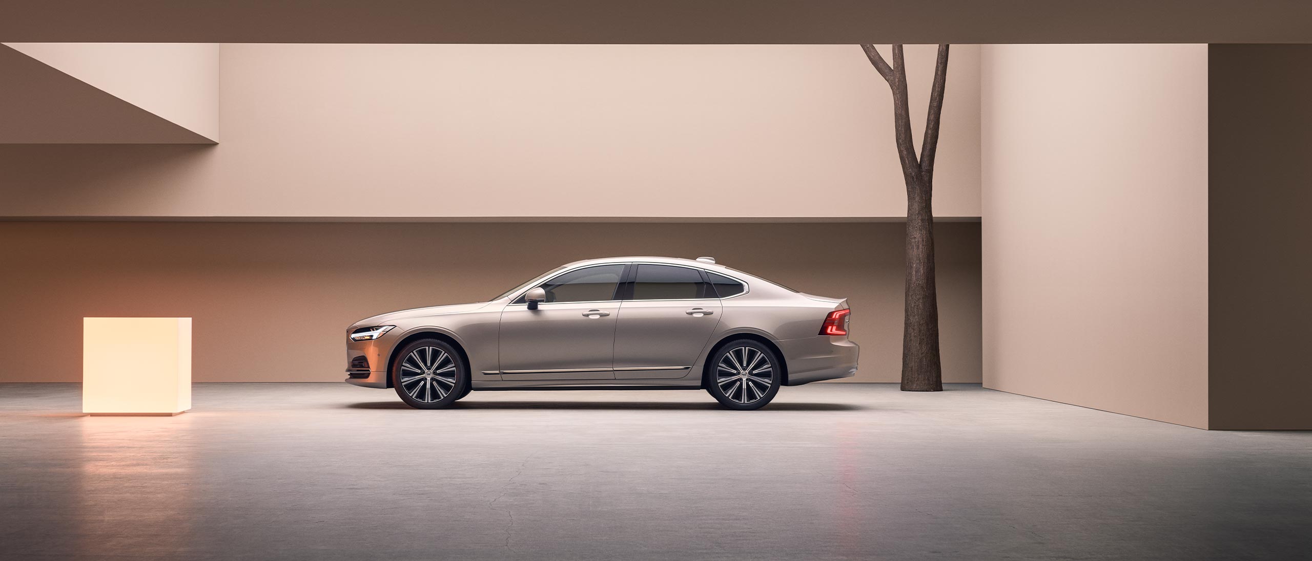 A wide-angle image of the left side of a Volvo S90 parked in a large concrete structure.