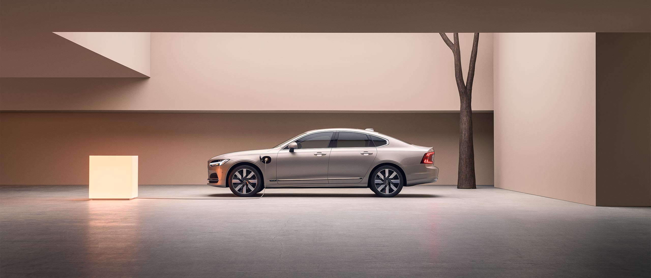 A wide-angle image of the left side of a Volvo S90 Plug-in hybrid parked in a large concrete structure.