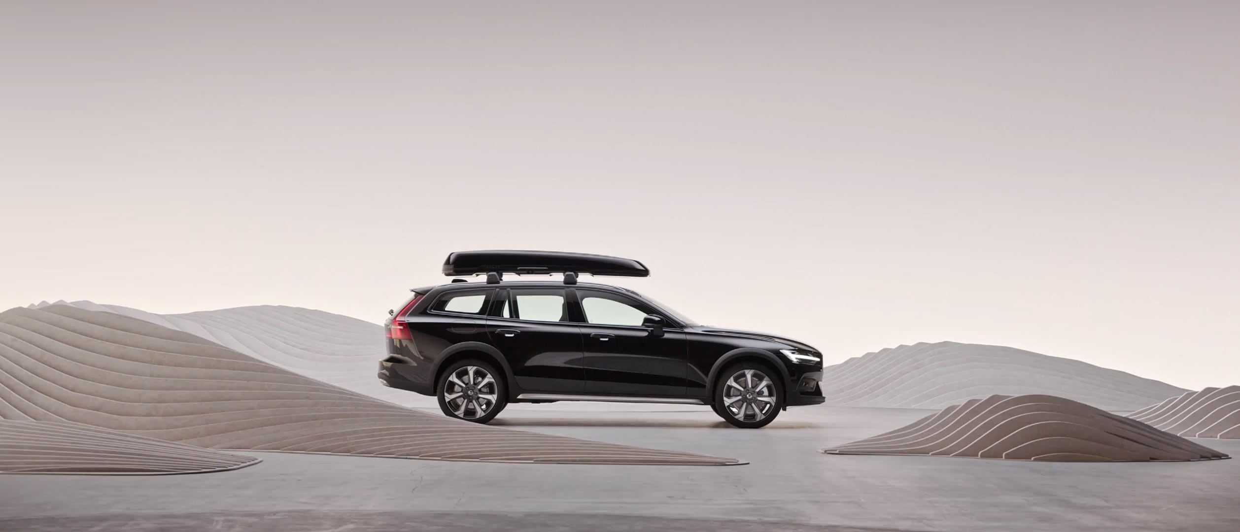 The side profile of a Volvo V60 Cross Country wagon with a roof box.