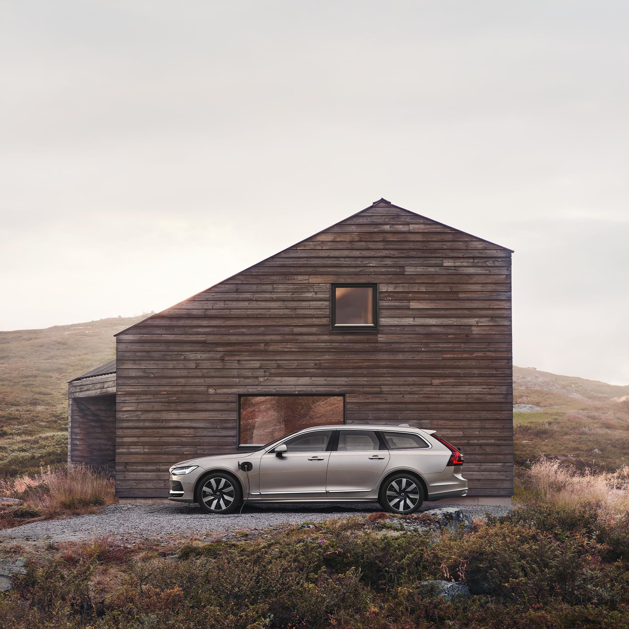 Volvo V90 recharge in front of a cabin in the mountains.