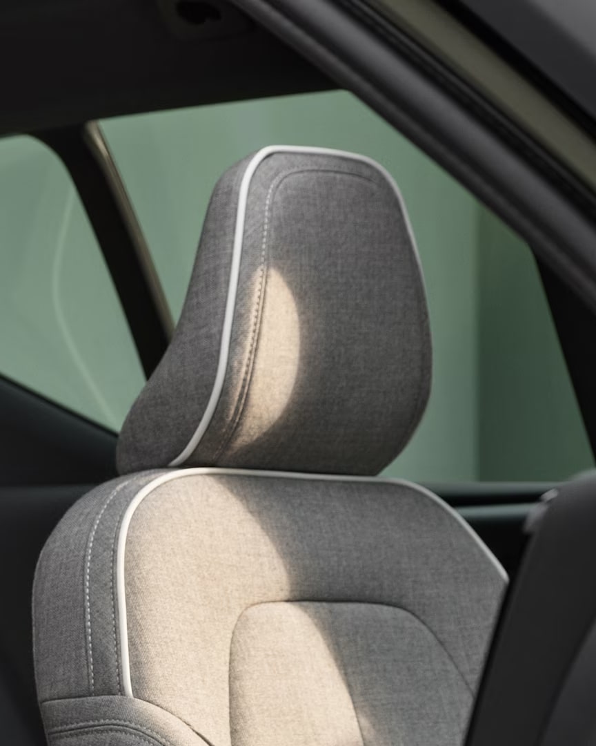 Los asientos del conductor y del pasajero delantero del Volvo XC40 Recharge eléctrico puro con tapicería gris en mezcla de lana a medida con ribetes blancos.