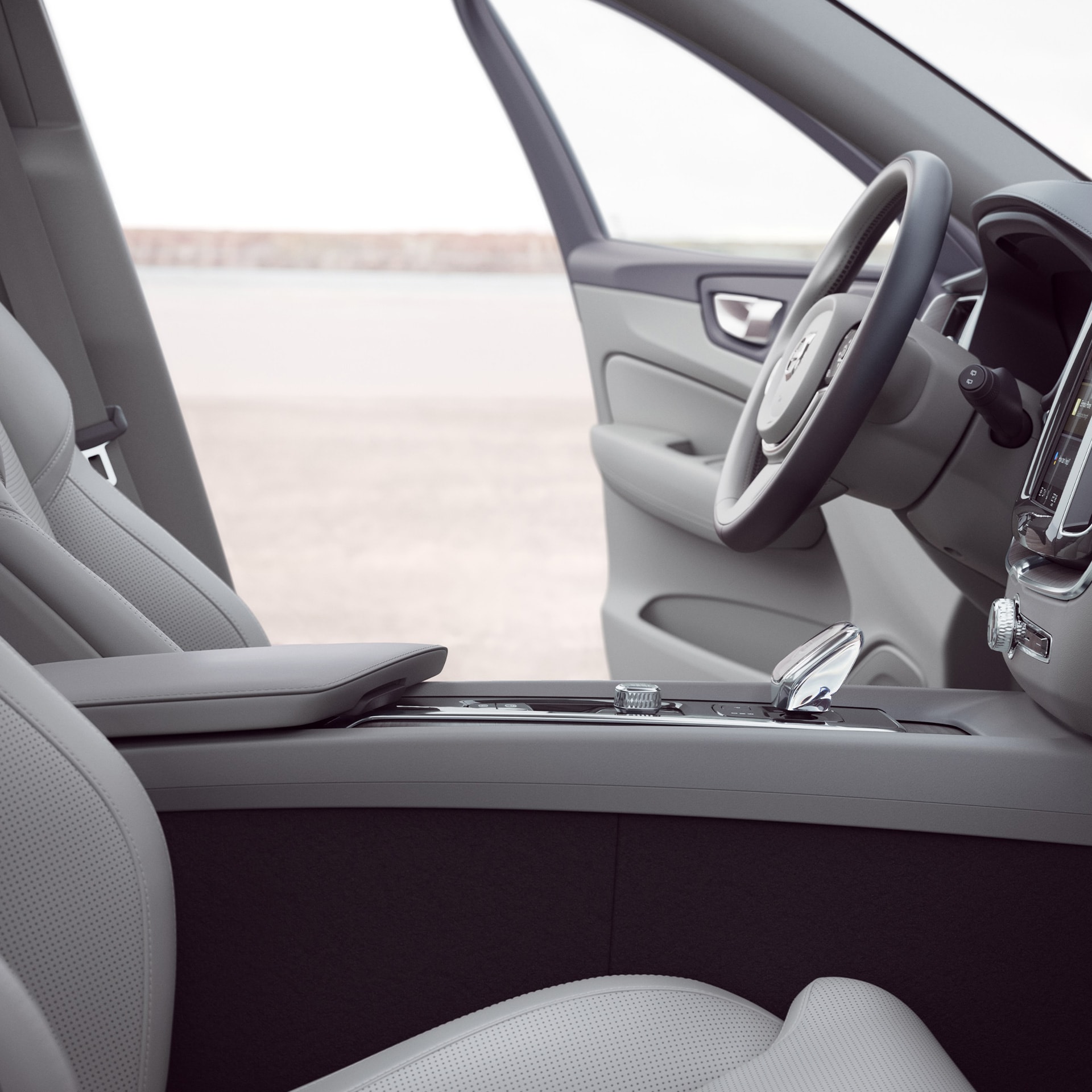 Οι εμπρός εσωτερικοί χώροι ενός Volvo XC60 με ανοιχτή την πόρτα του οδηγού.