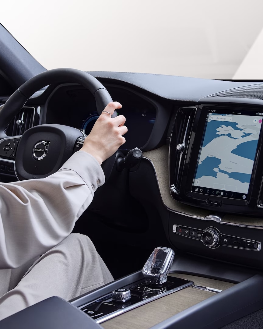 Interior view showing a woman driving a Volvo XC60 Recharge with map view on center console.