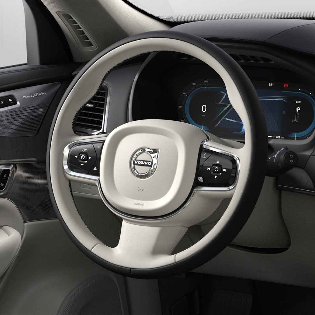 Two-tone beige and black steering wheel, instrument panel and driver-side door in the Volvo XC90 mild hybrid SUV.