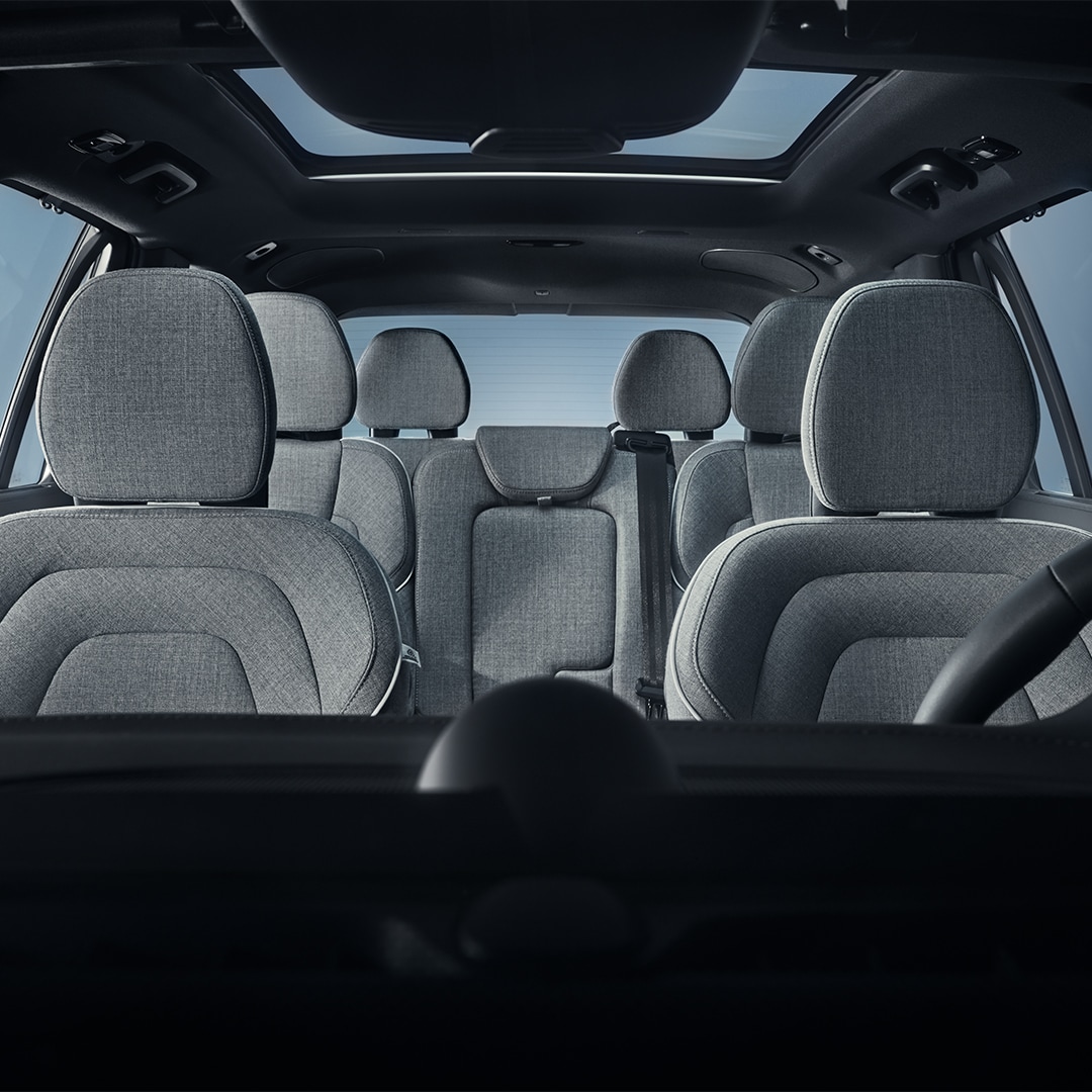 Weitwinkelblick auf sieben gepolsterte Sitzplätze aus Wolle im Innenraum eines Volvo XC90 Recharge Plug-in Hybrid.