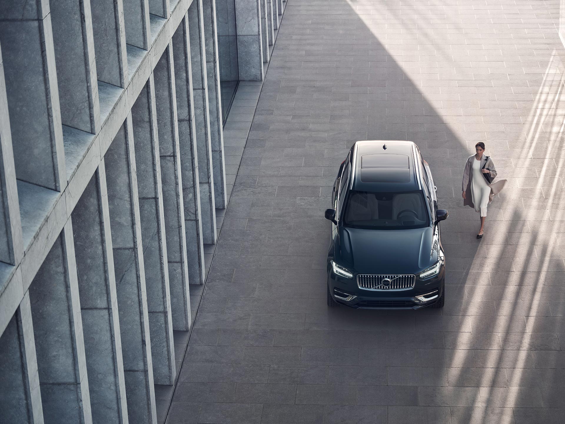 A person walking up to a Volvo XC90 Recharge plug-in hybrid.