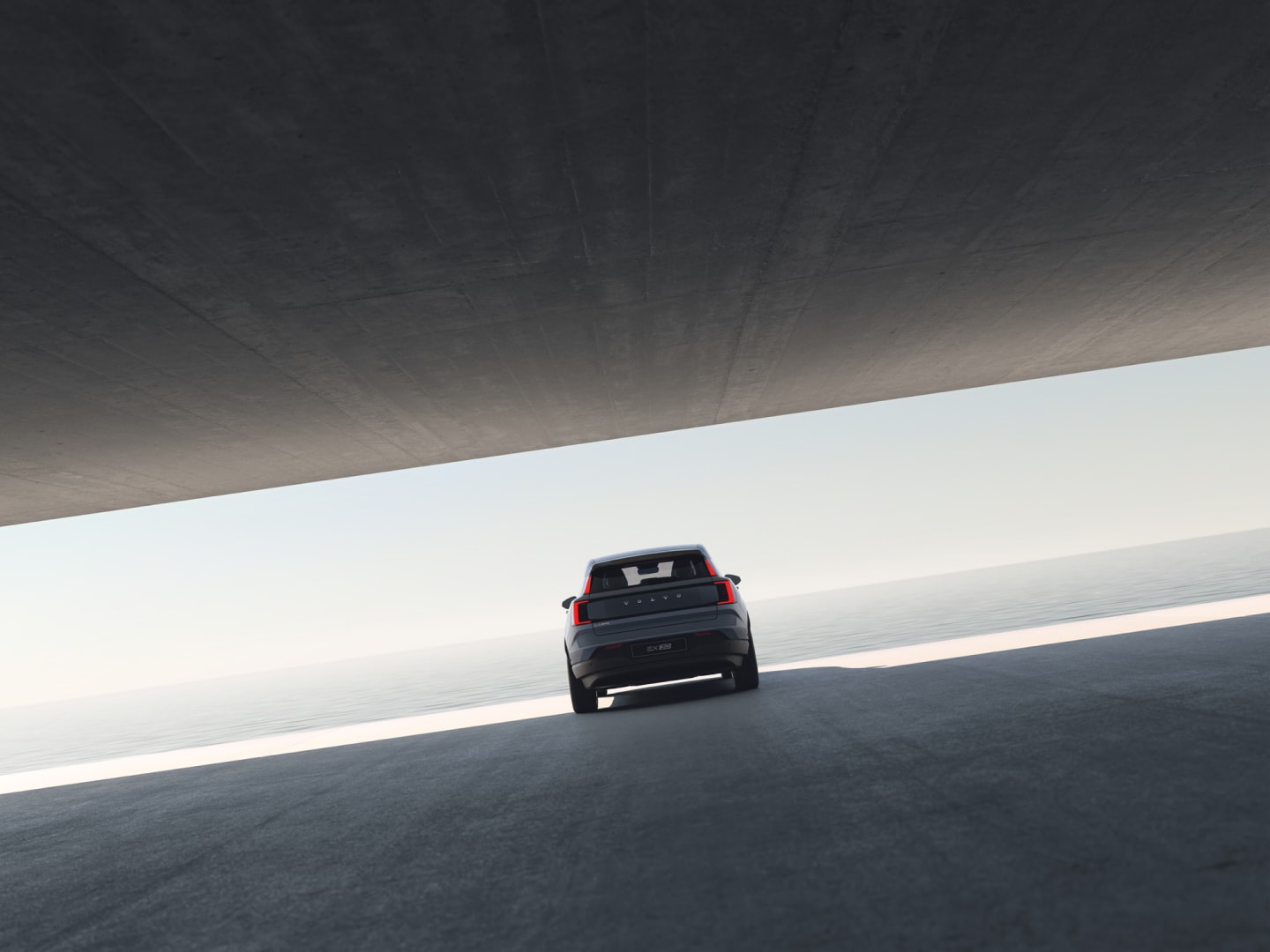 Pohľad zozadu na Volvo EX30 zaparkované vedľa otvorenej betónovej konštrukcie nad vodou.
