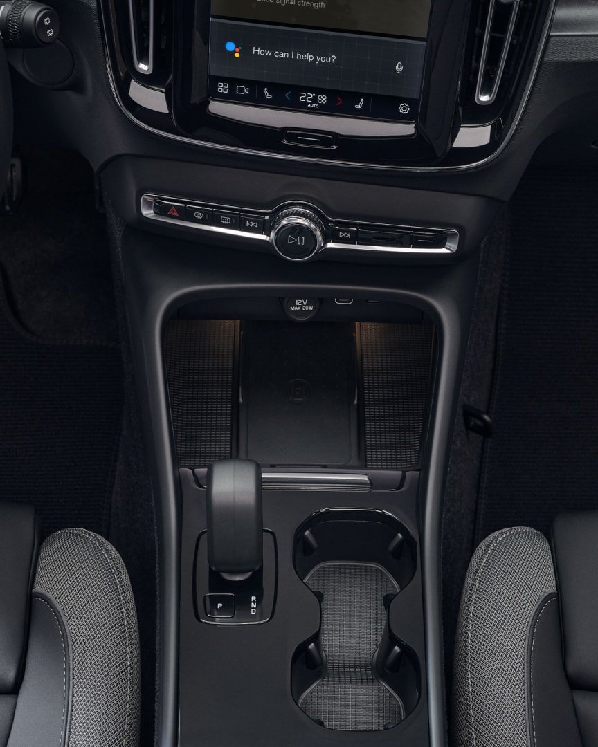 Suportul pentru pahar, schimbătorul de viteze și încărcătorul wireless poziționate între scaunele față ale modelului Volvo EX40 integral electric.