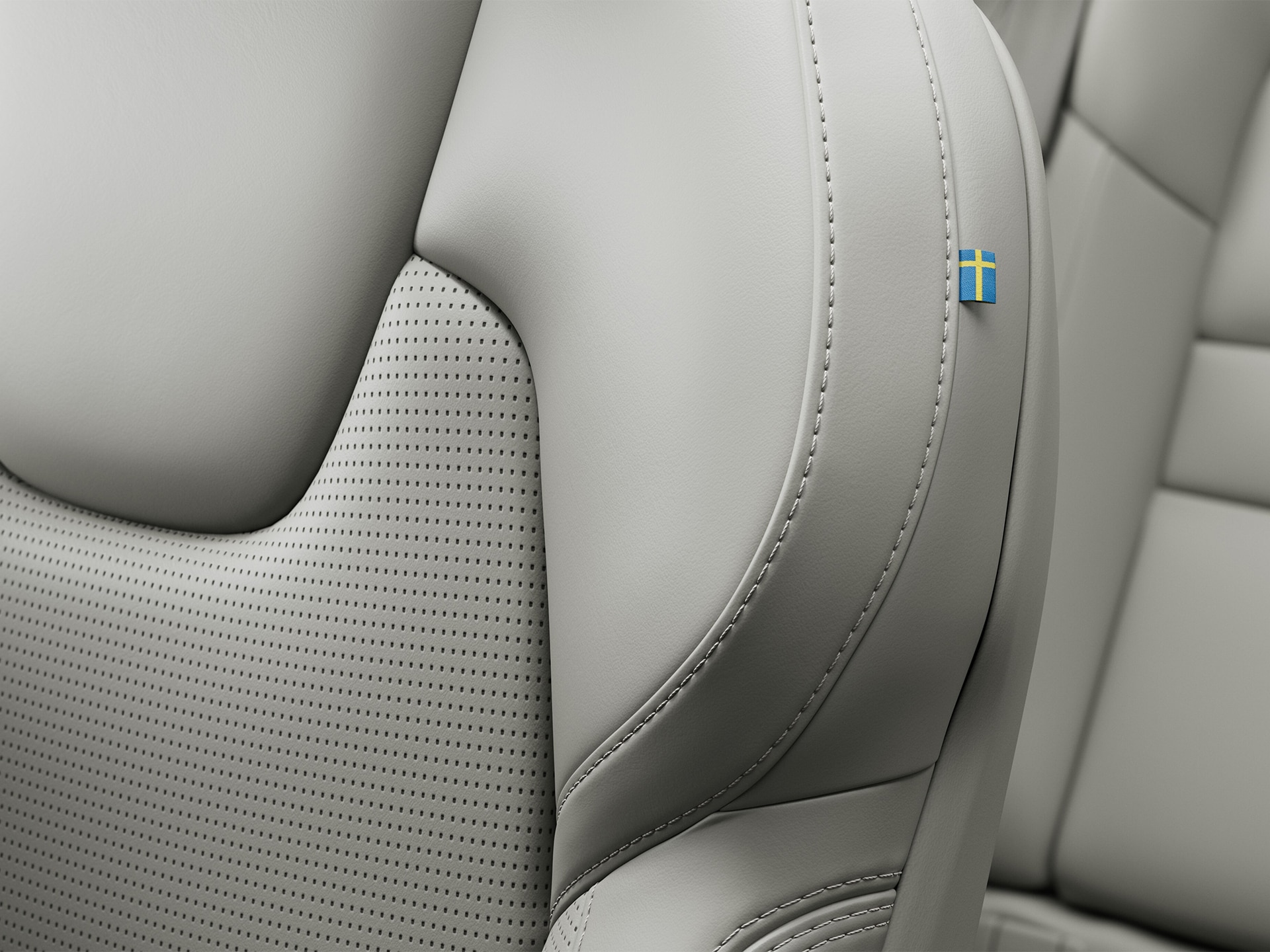 Detalle de las costuras del asiento del copiloto en cuero de Napa del semihíbrido Volvo V60 con una pequeña bandera sueca.