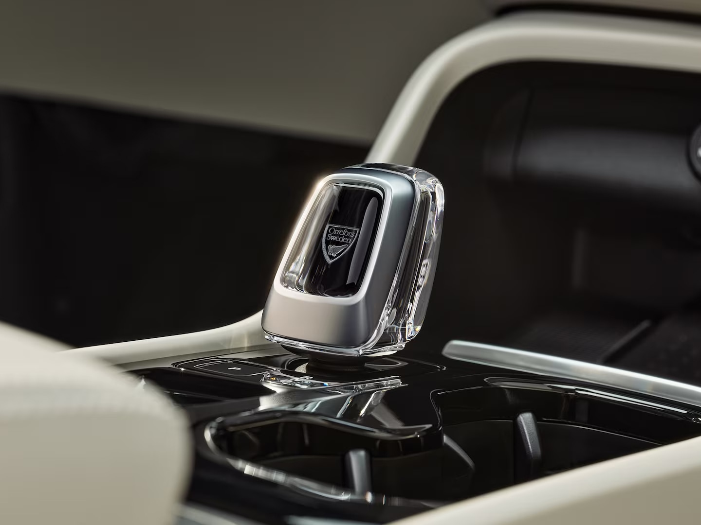 Prim-plan cu schimbătorul de viteze din cristal pe consola centrală neagră, lucioasă, a modelului Volvo XC40 mild hybrid.