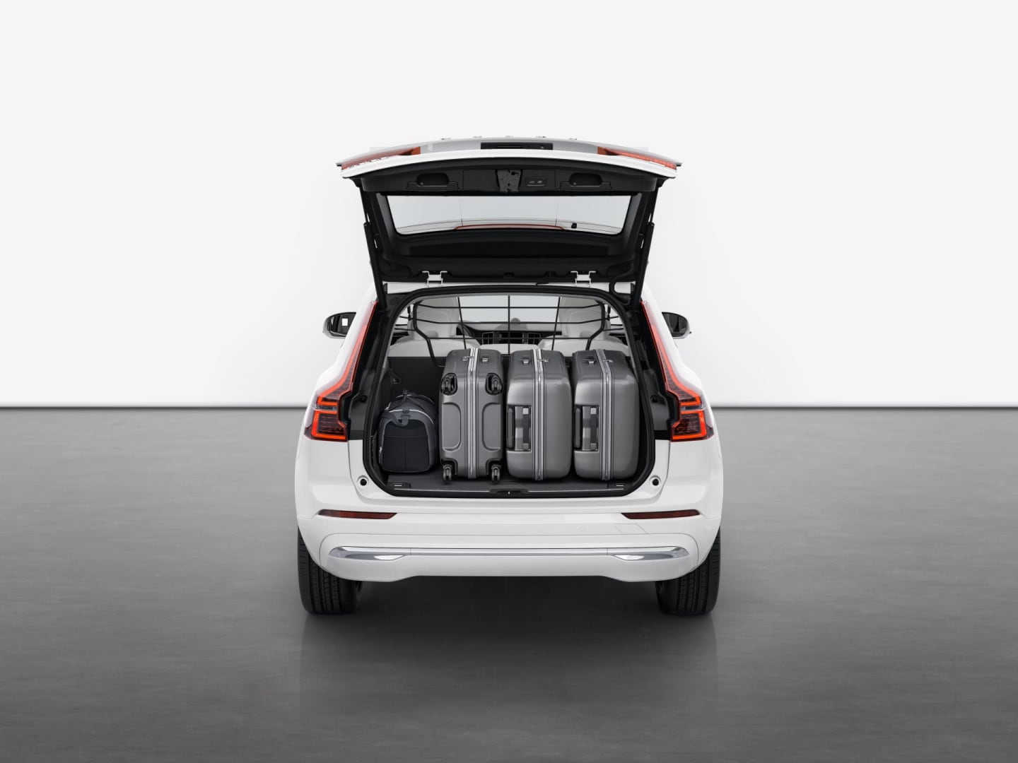 Vista posteriore di Volvo XC60 con il baule aperto che mostra la quantità di bagagli sistemabili.