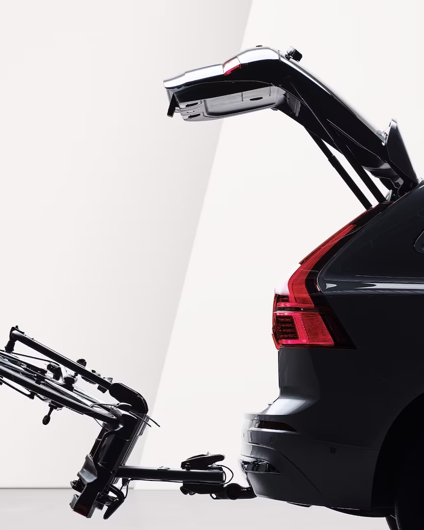 Otevřené dveře zavazadlového prostoru a sklopený nosič jízdních kol na tažném zařízení vozu Volvo XC60.