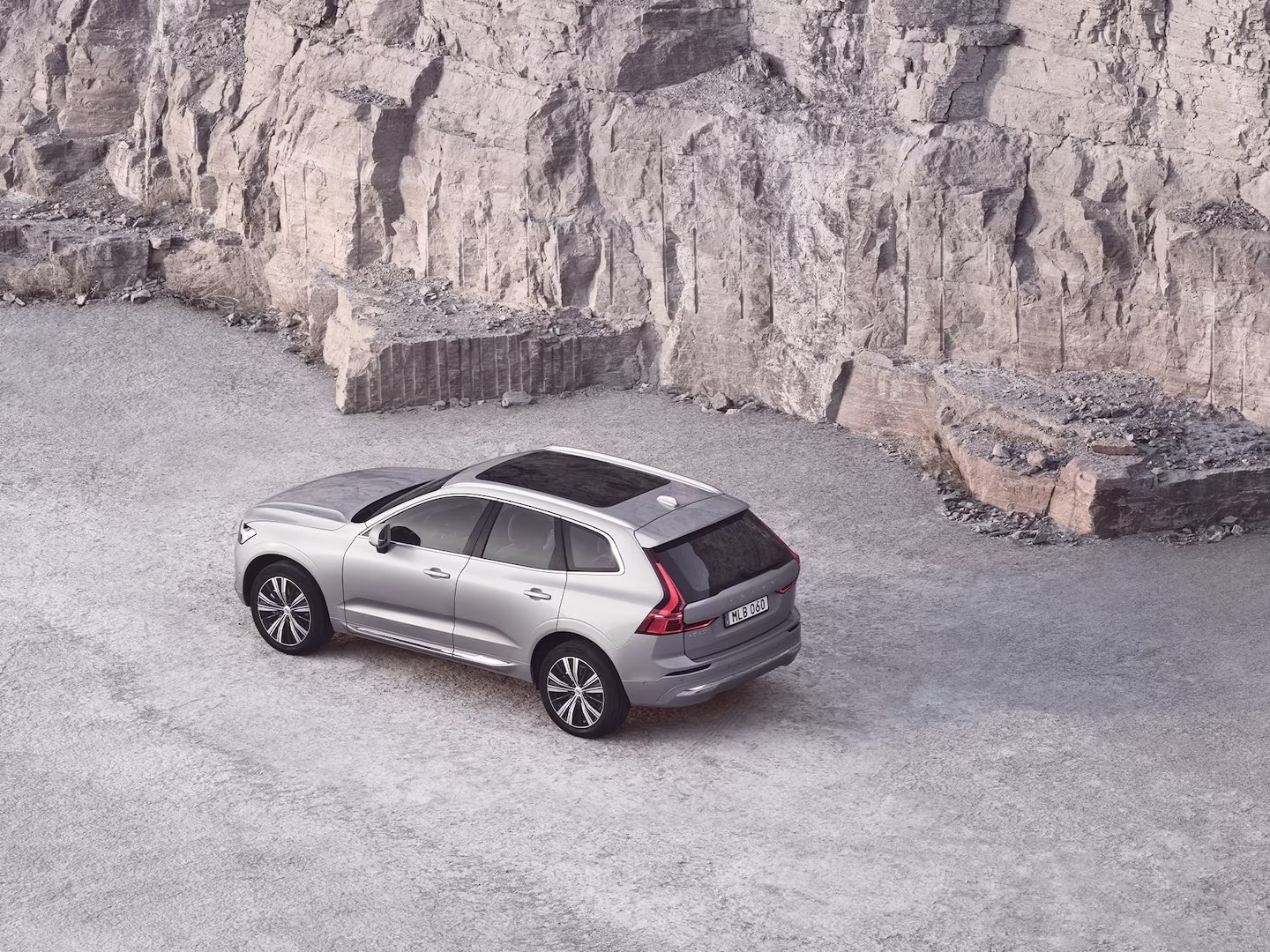 A Volvo XC60 with a panoramic roof next to a rock wall.