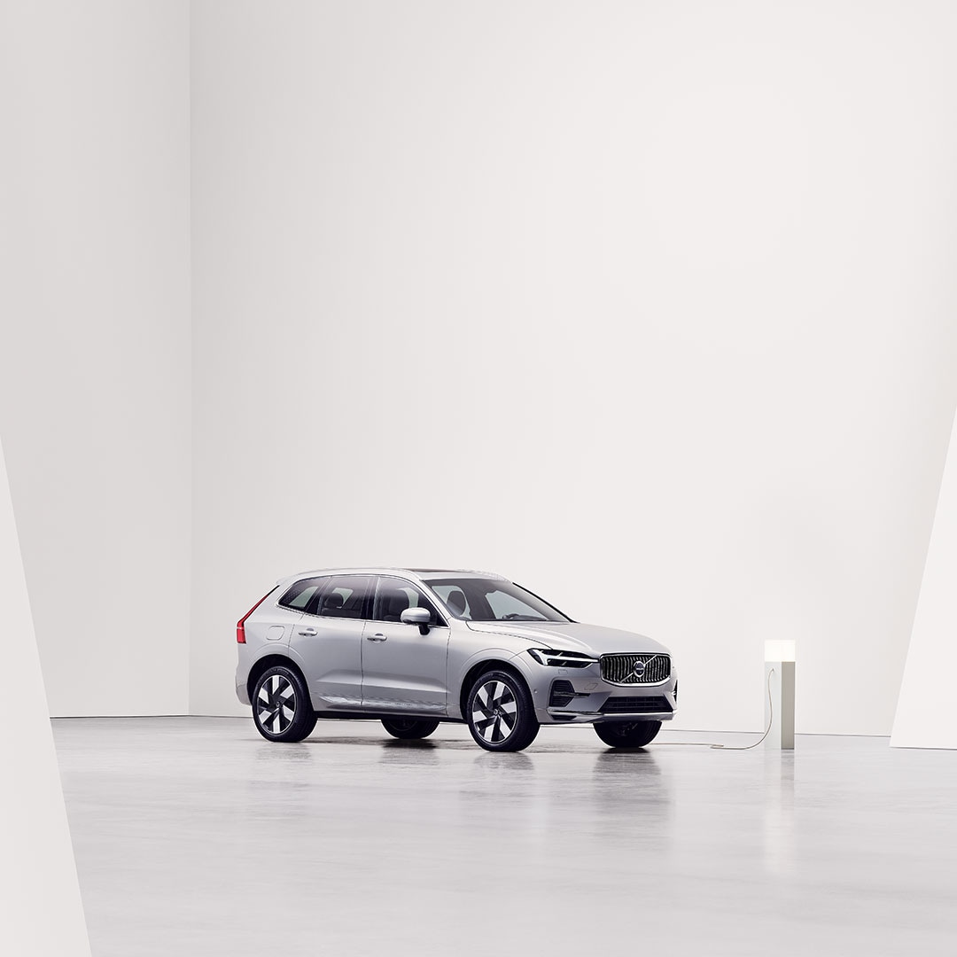 Side view of Volvo XC60 plug-in hybrid being charged at charging station.