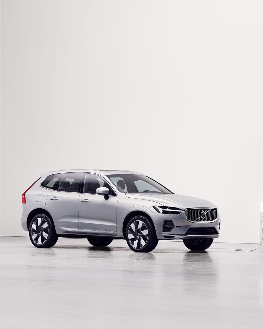 Side view of Volvo XC60 plug-in hybrid being charged at charging station.