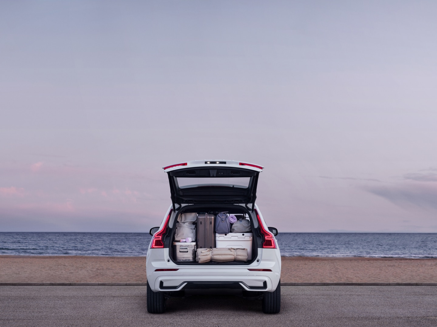 Rear view of a Volvo XC60 plug-in hybrid with the trunk open showing the amount of luggage that fits.