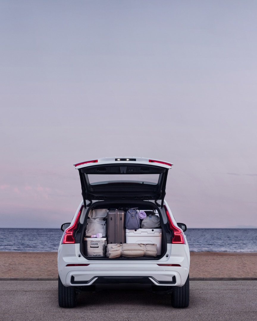 Rear view of a Volvo XC60 plug-in hybrid with the trunk open showing the amount of luggage that fits.
