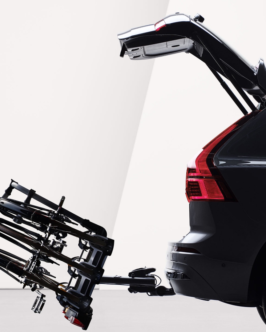 An open tailgate and a bicycle holder attached by tow bar folded down on the rear of a Volvo XC60 plug-in hybrid.