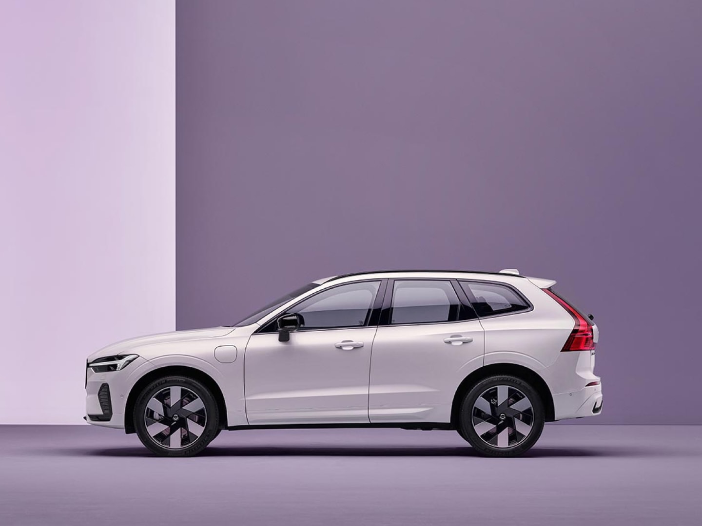 Un Volvo XC60 hybride rechargeable en charge dans un environnement blanc.
