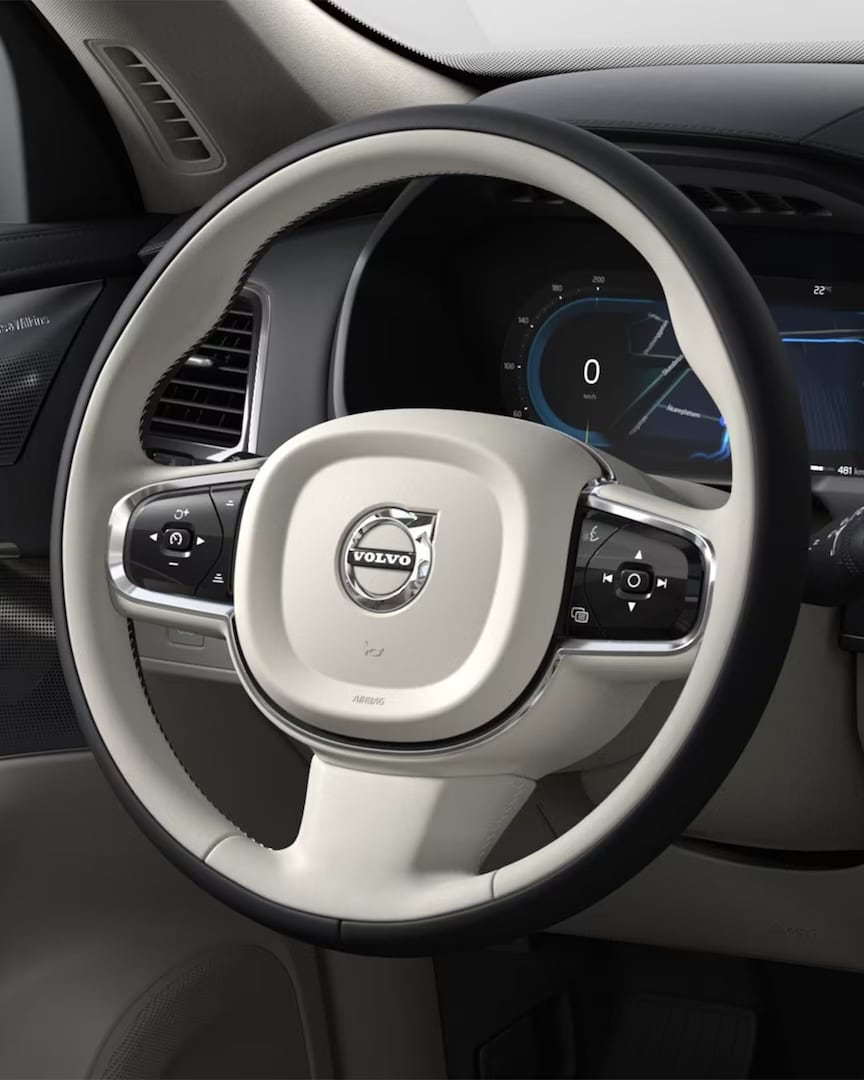 Two-tone beige and black steering wheel, instrument panel and driver-side door in the Volvo XC90 mild hybrid SUV.