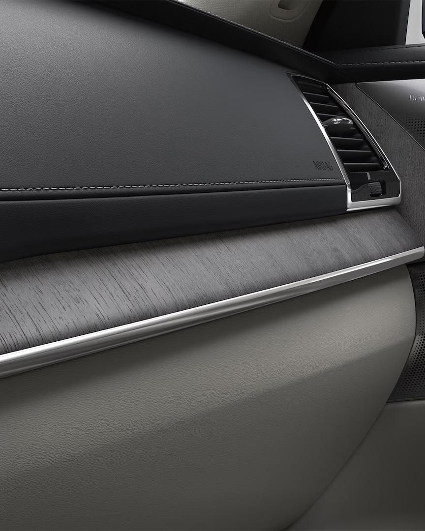 Deska rozdzielcza po stronie pasażera z czarno-beżową tapicerką i dekoracją drewnianą w SUV-ie Volvo XC90 w wersji miękkiej hybrydy