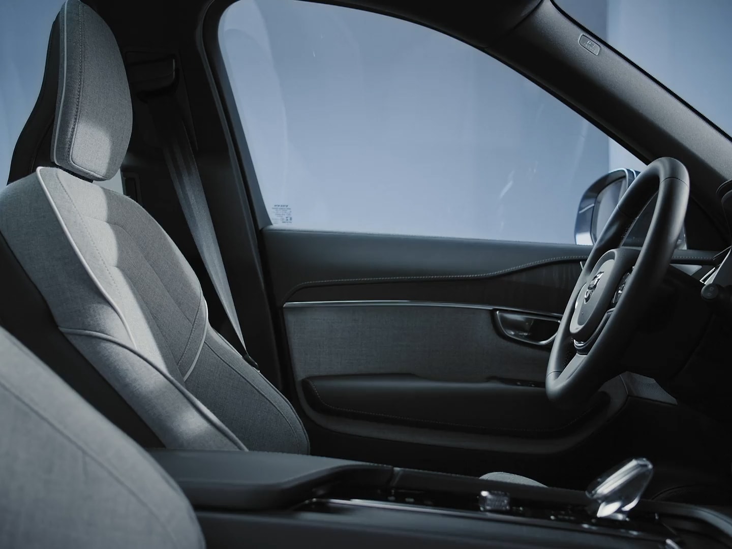 Passenger view of the Volvo XC90 plug-in hybrid driver’s seat and door in wool upholstery and black steering wheel.