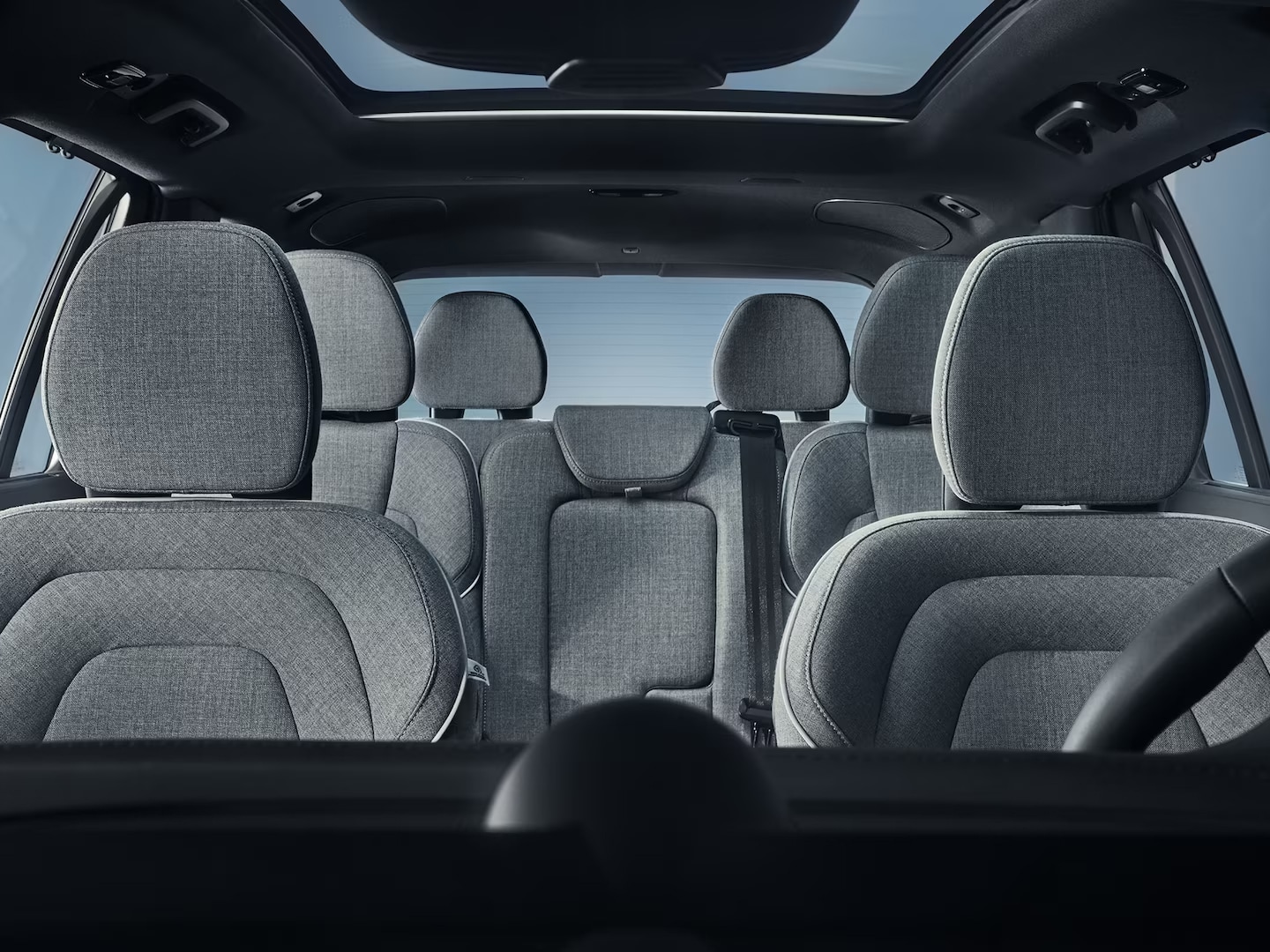 Vista grandangolare di sette sedili con rivestimento in lana nell'abitacolo della Volvo XC90 plug-in hybrid.